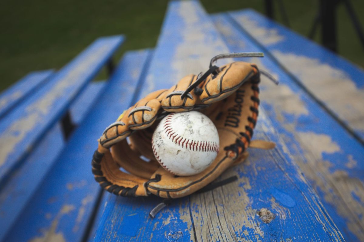 A white baseball in a leather baseball glove, on a blue bleacher