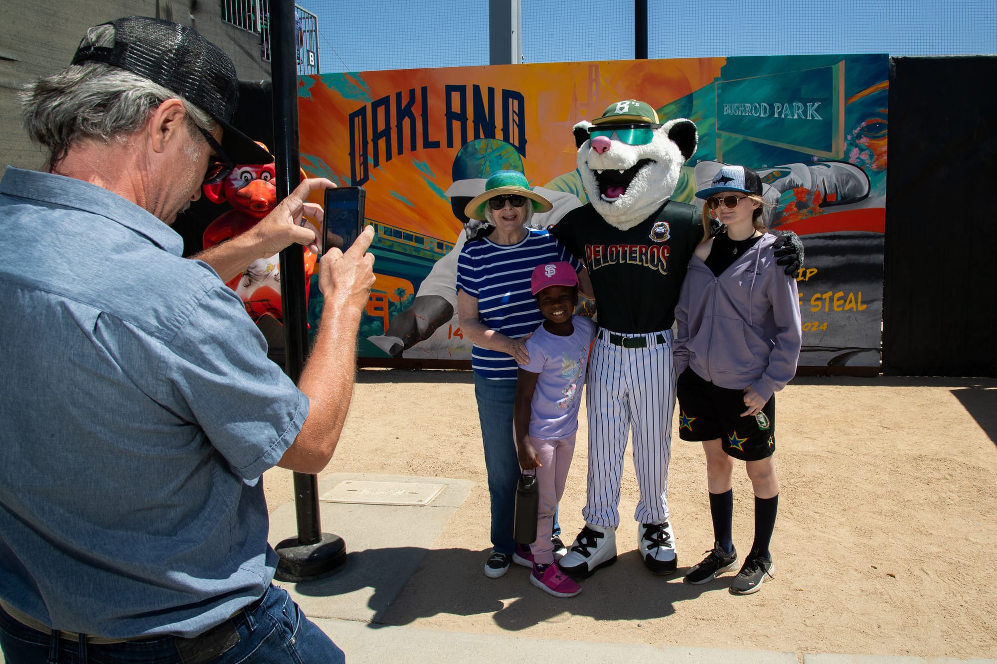 A person in a possum mascot costume poses for a photo with three people.