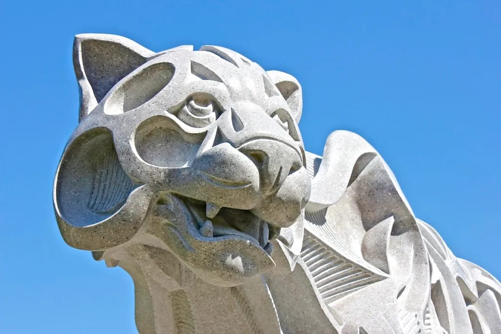 The face of a white puma made of stone, sculpted in an angular, abstracted style.