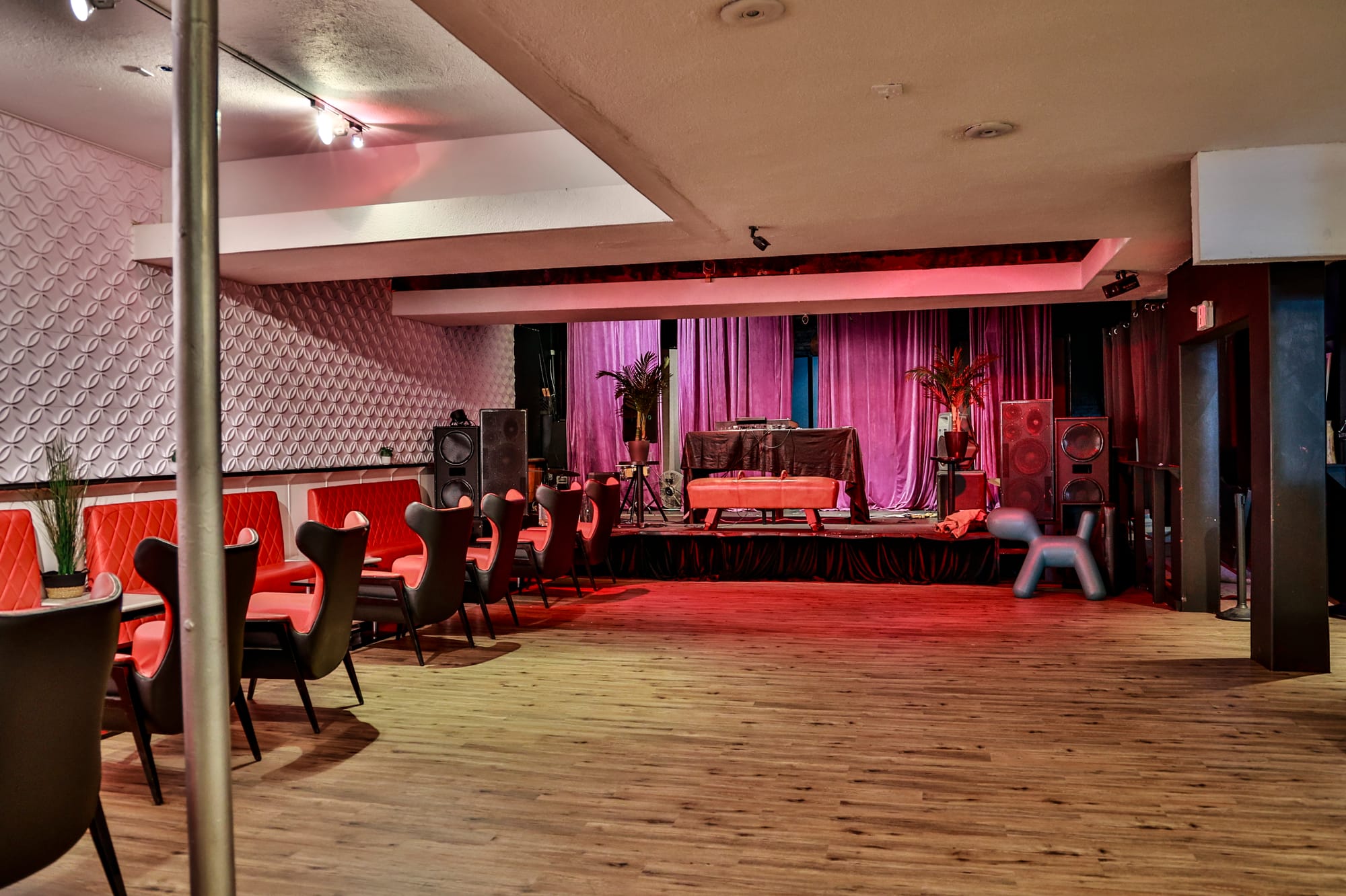 a stage at a basement venue bathed in red light, with hardwood floors