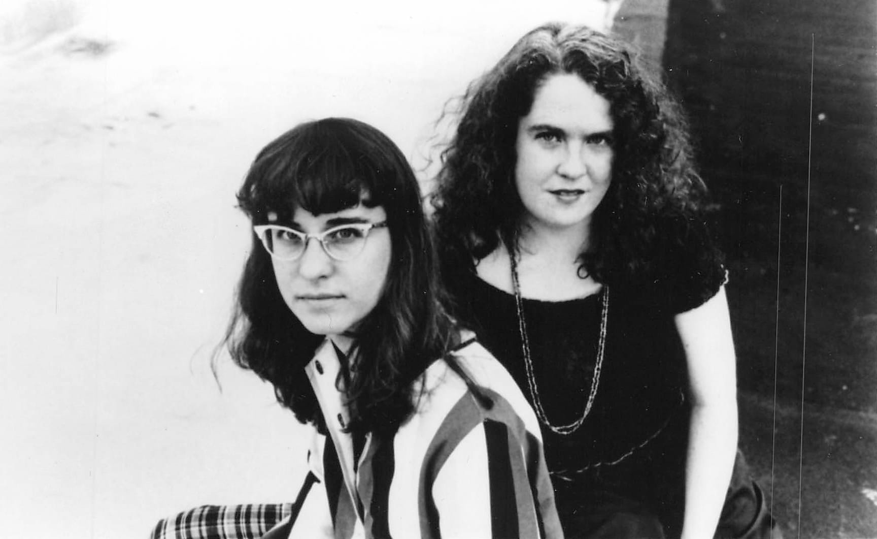 two women with dark hair smile in a black and white photo from 1995