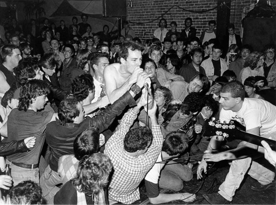 a black and white photo of Dead Kennedys frontman Jello Biafra singing into a microphone at Mabuhay Gardens in San Francisco