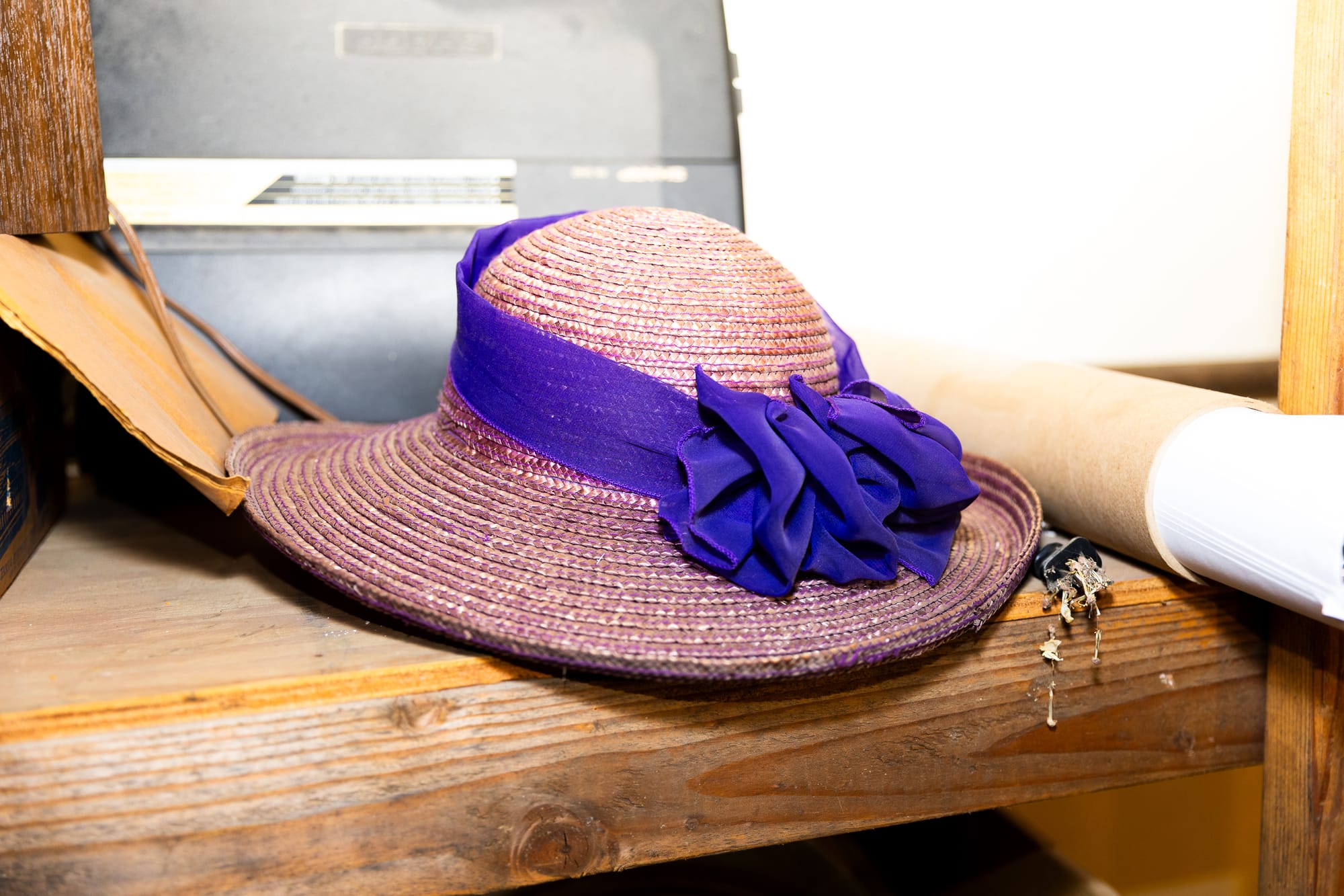 A straw, purplish hat with a wide brim and purple ribbon