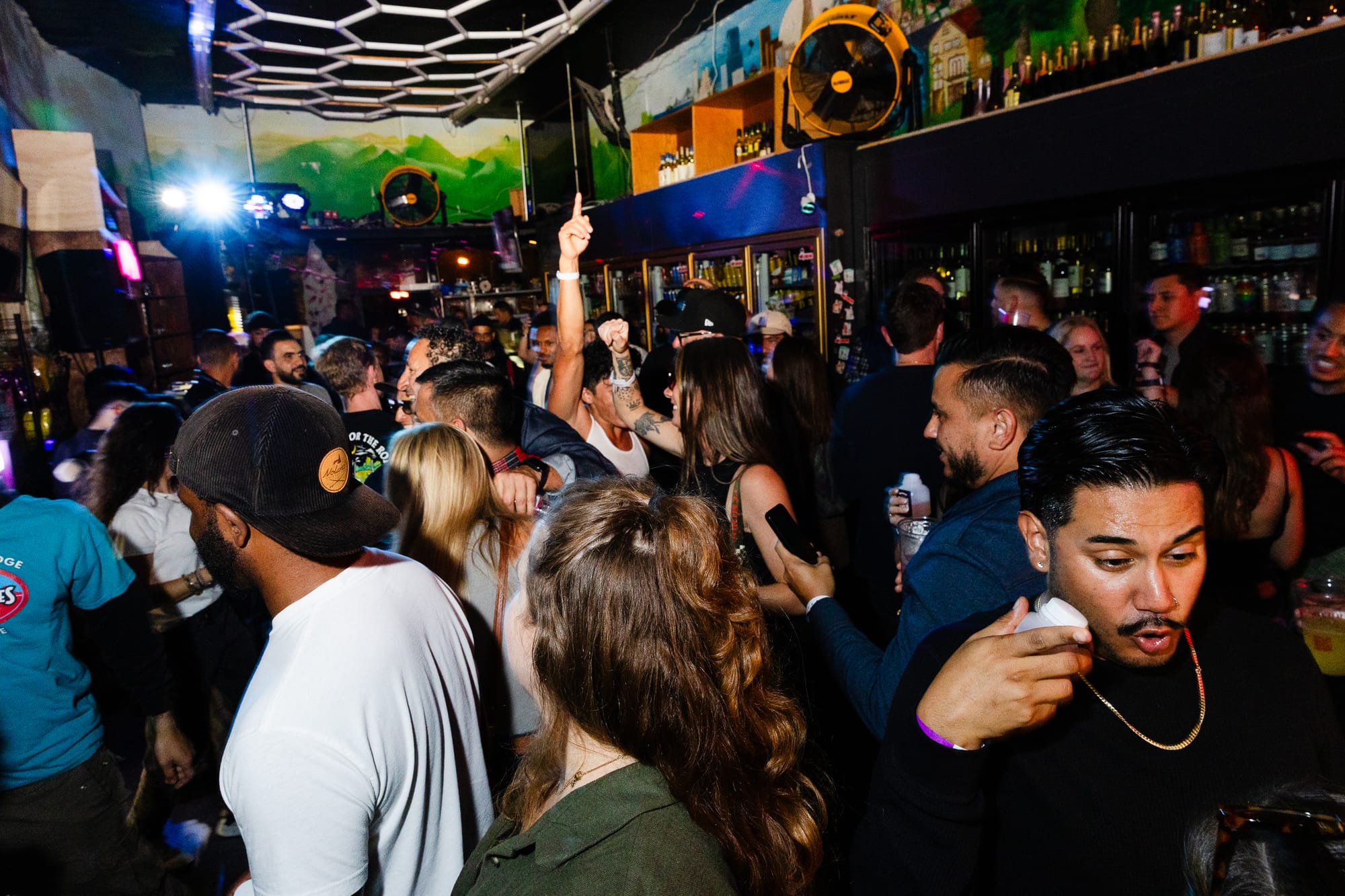 Dozens of people dance inside of a Liquor store as a DJ performs. 