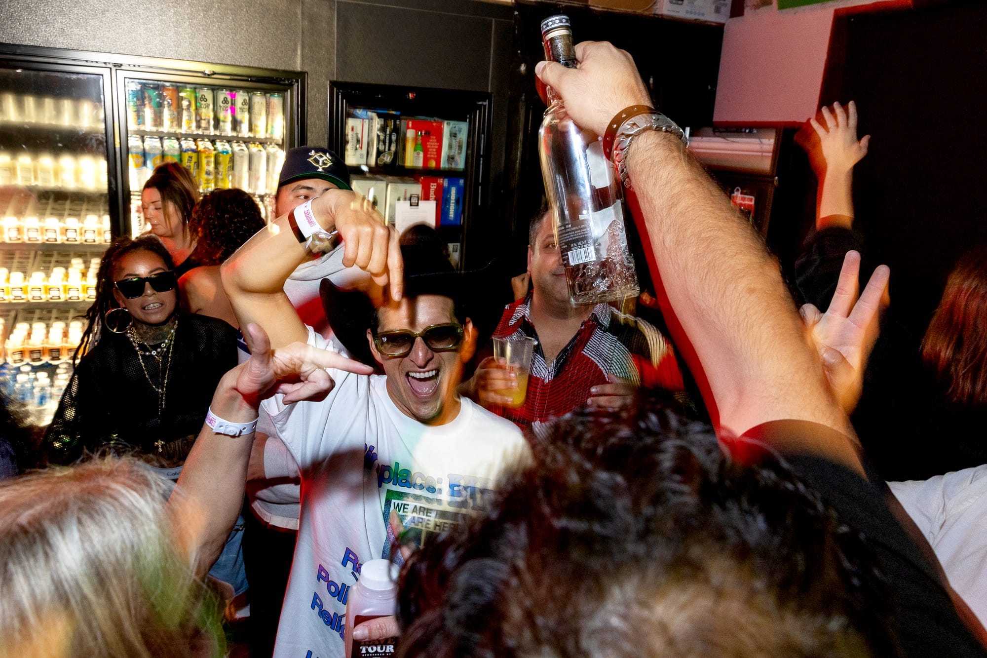Several people with drinks in their hands cheer. 