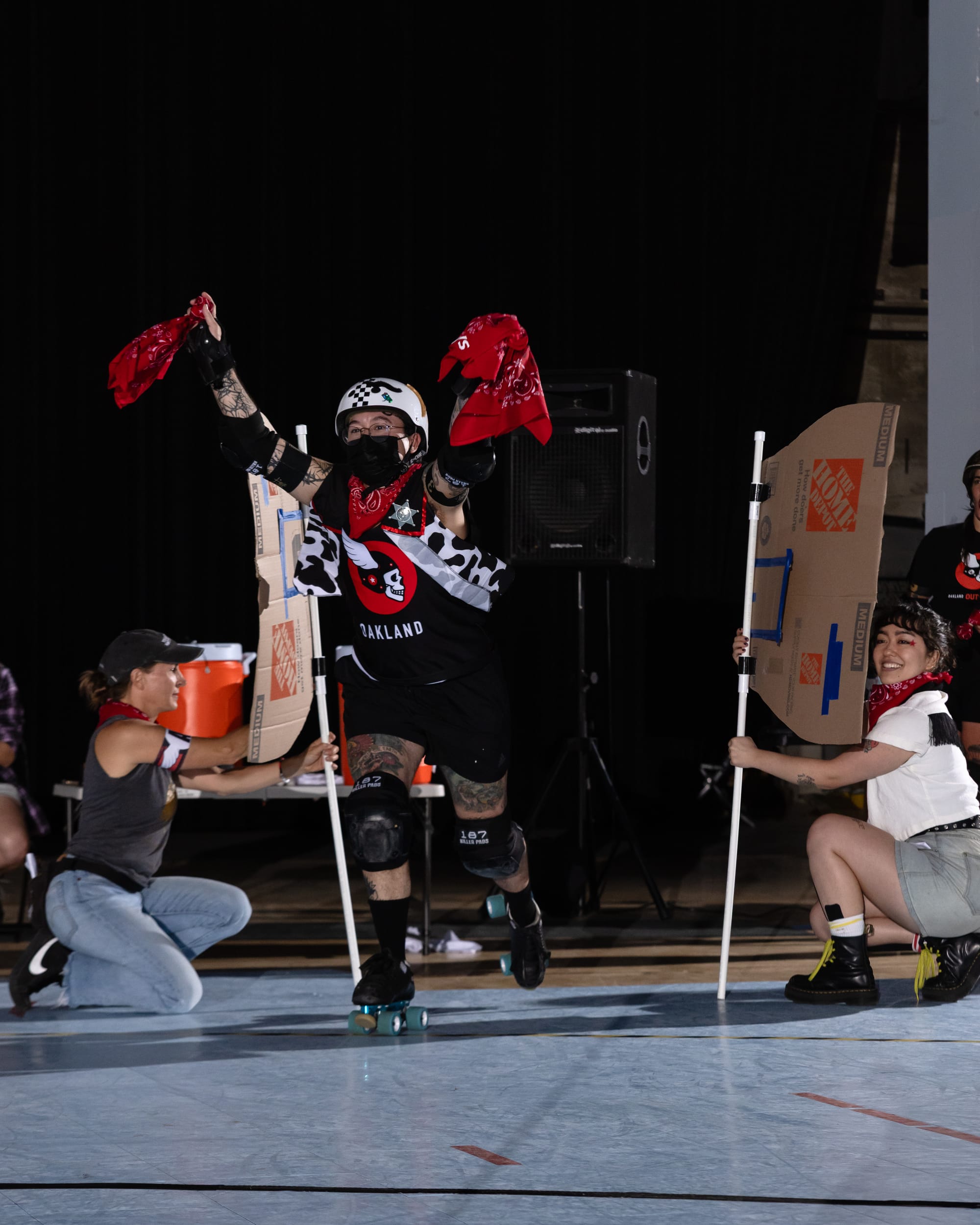 A skater holding two red bandanas skates through two "saloon doors" made of cardboard and PVC pipe