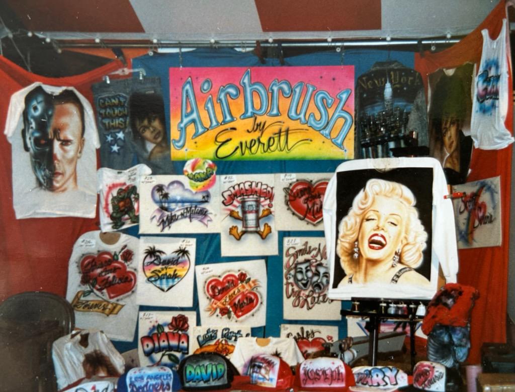 An airbrush merch stall featuring portraits of Marilyn Monroe and the Terminator.