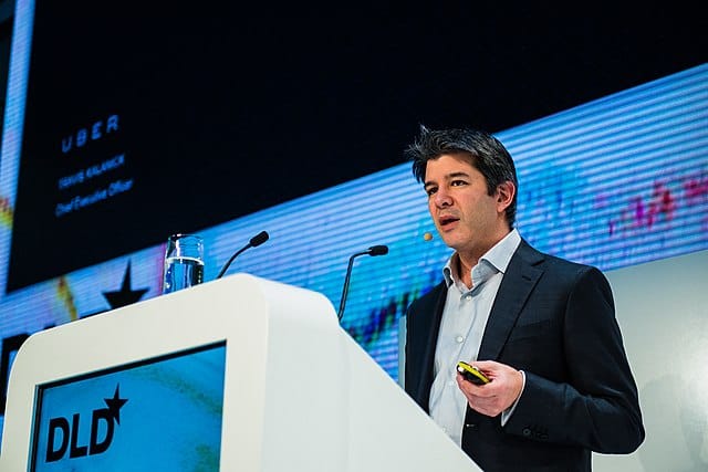 Travis Kalanick, then the CEO of Uber, stands behind a podium talking 