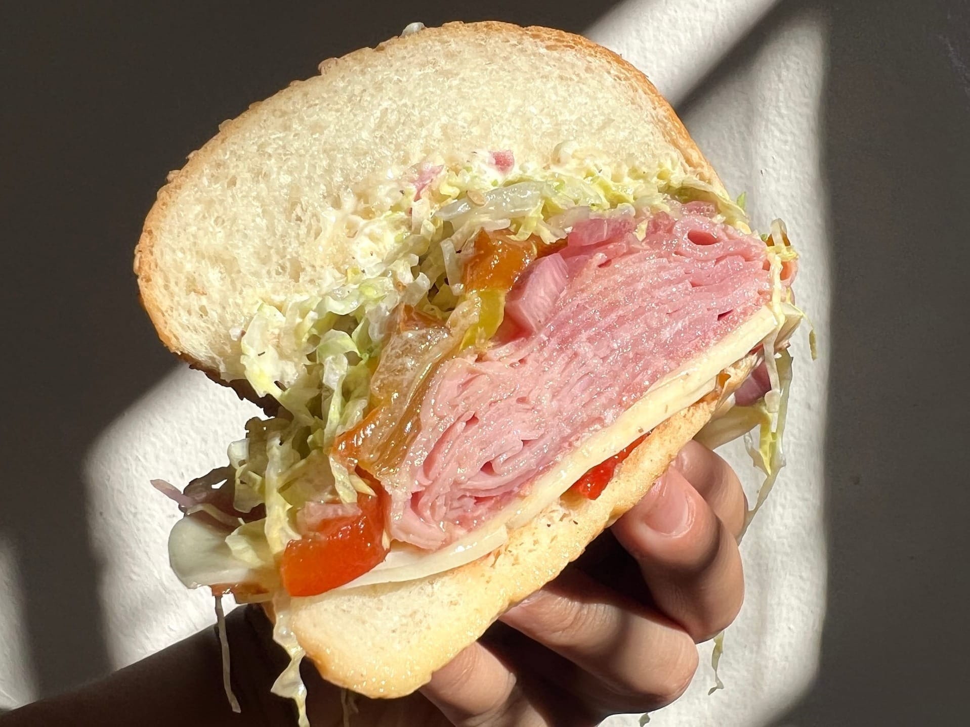 Close-up of half of an Italian-style hoagie with cold cuts, shredded lettuce, and cheese.
