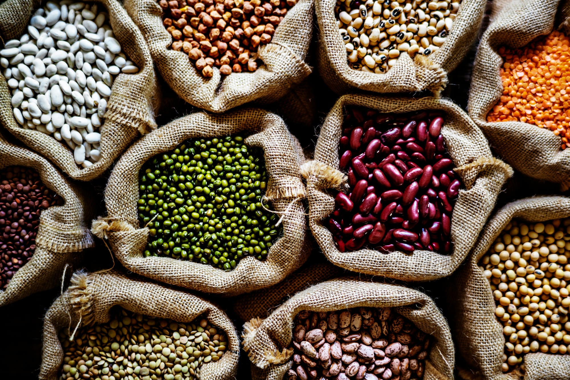 Various types of beans displayed in sacks.