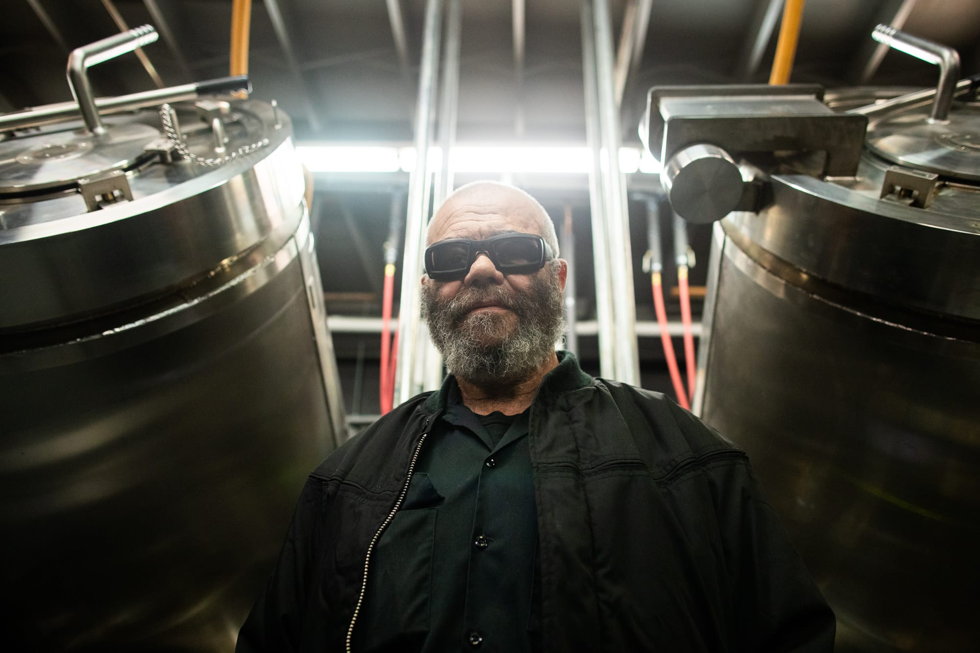 Man in black wearing sunglasses standing in front of two aquamation machines.