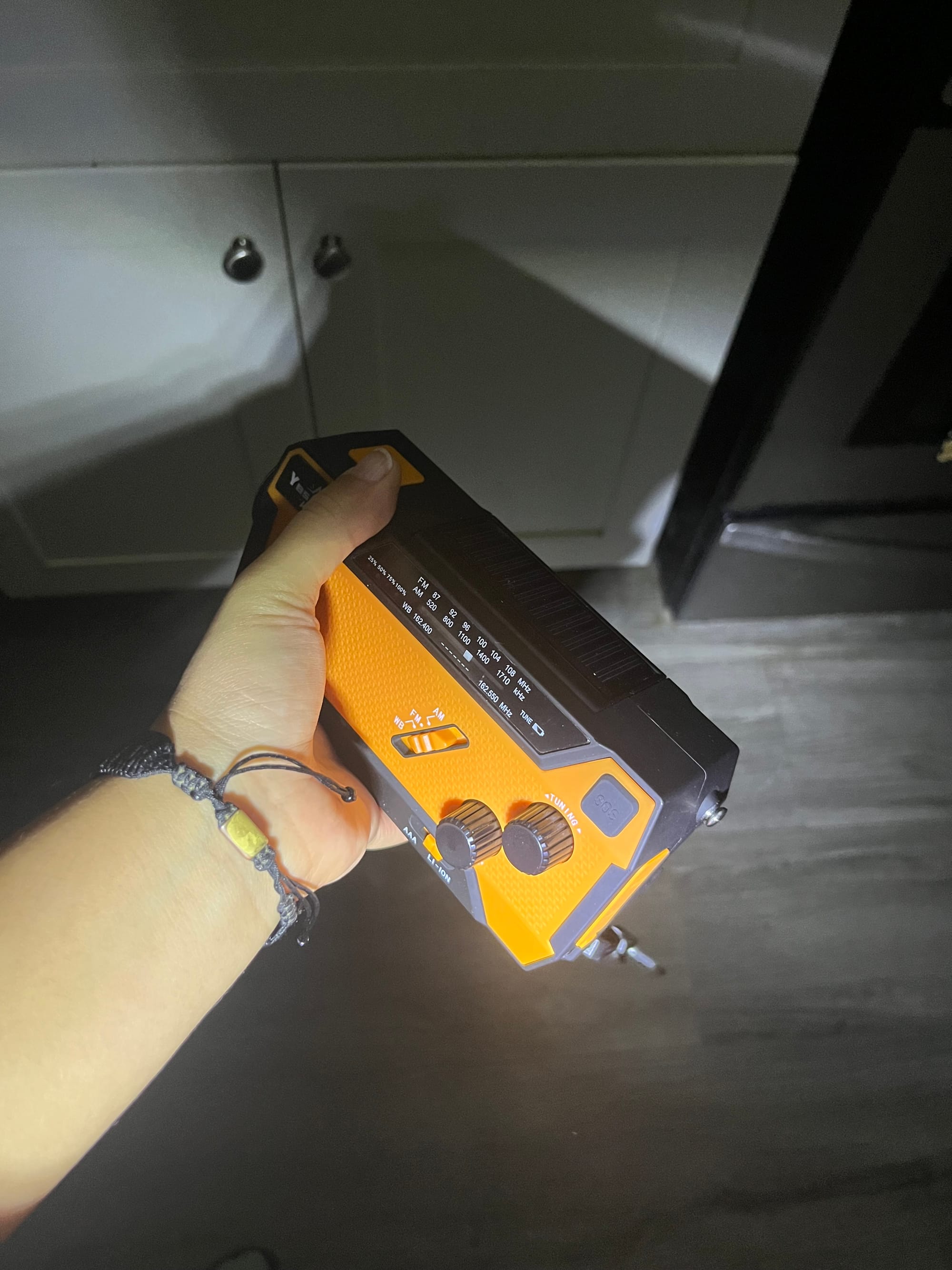 a hand holds an emergency radio in the darkness