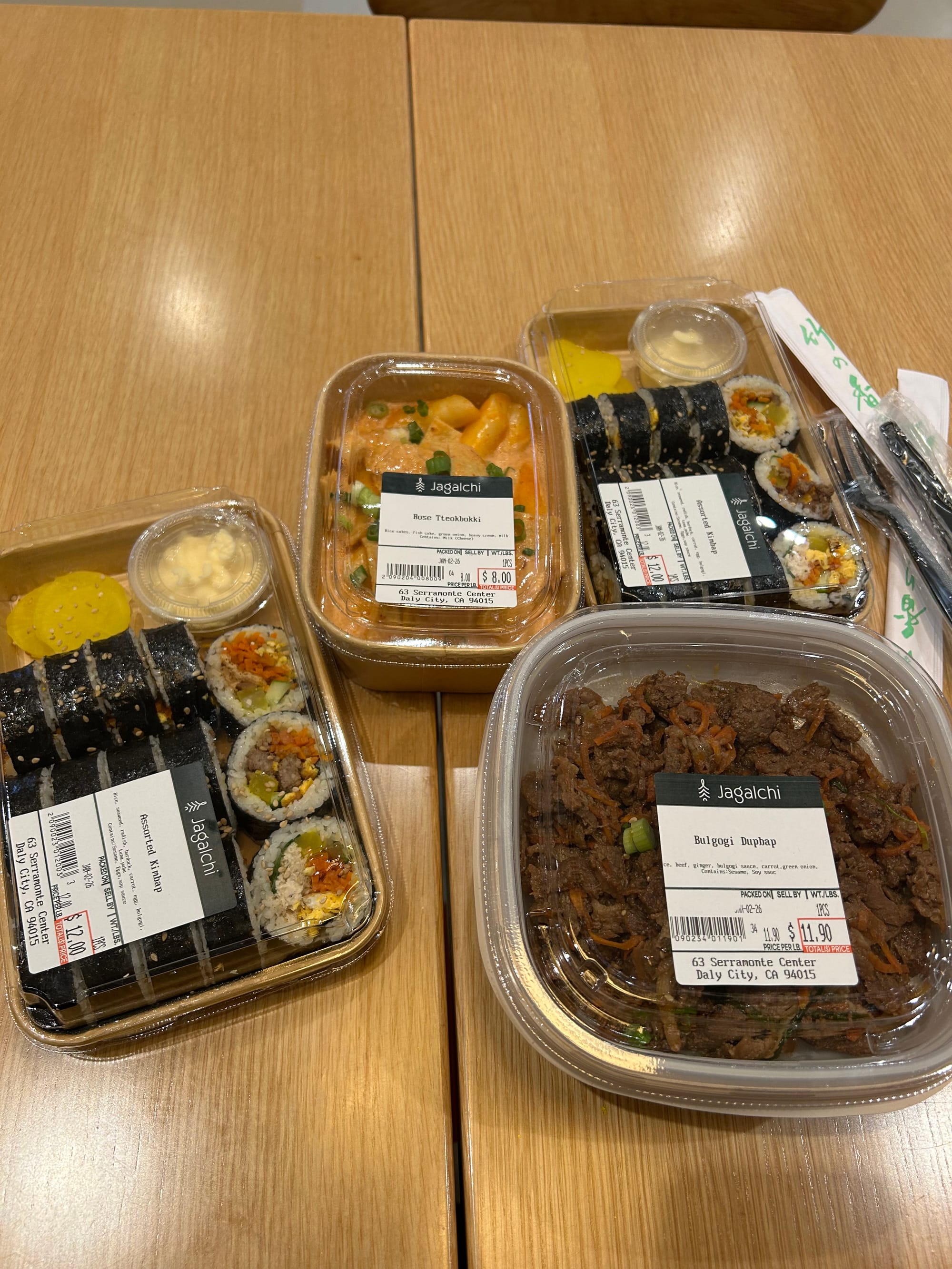 Takeout prepared food from Jagalchi, including bulgogi, kimbap, and rose tteokbokki.