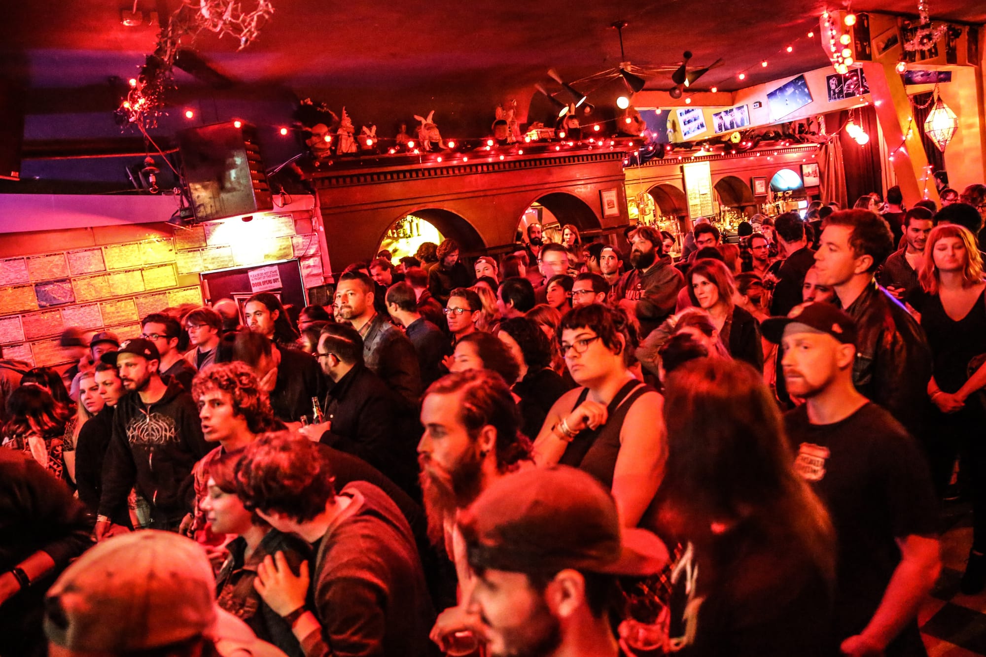 a large crowd in a red light-tinted music venue
