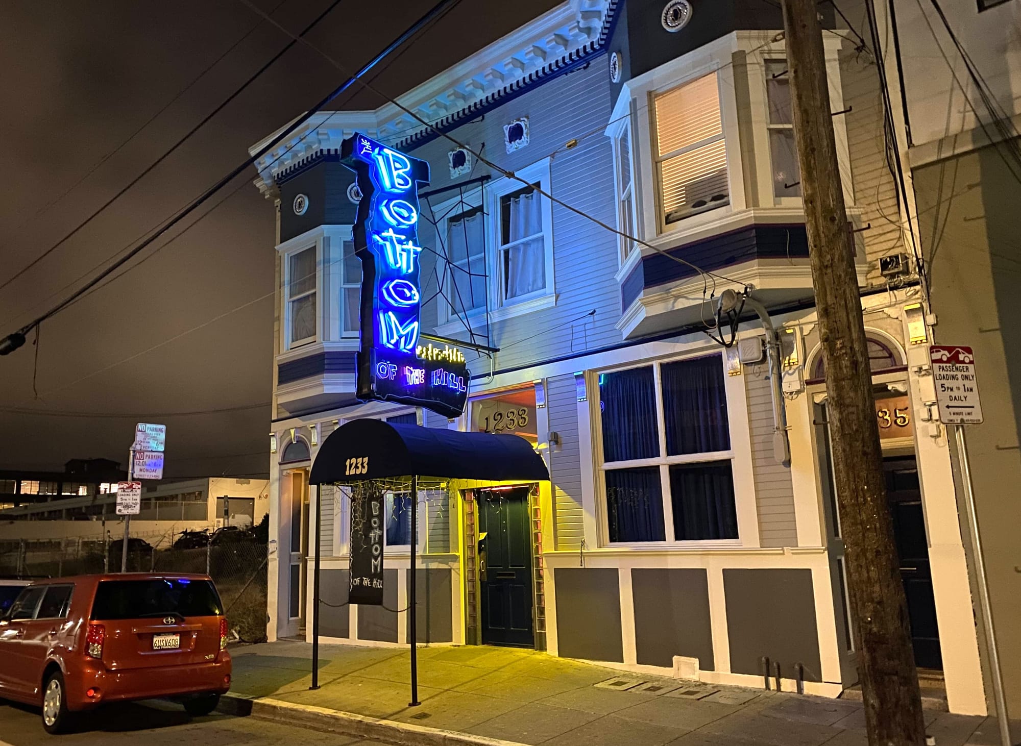the exterior of a music venue called Bottom of the Hill, with a blue L-shaped neon sign