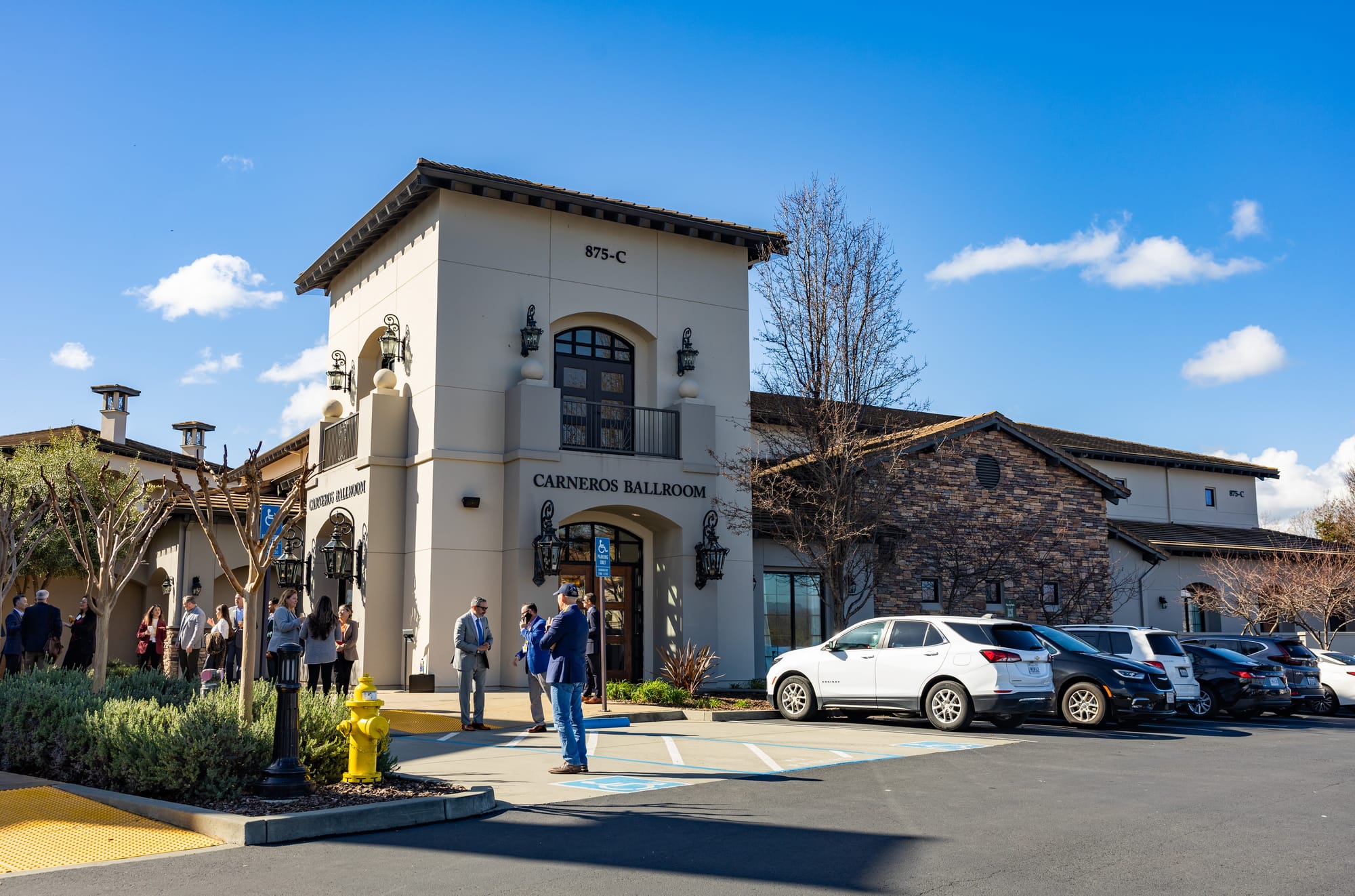 People in business clothing stand outside of a conference hall at a resort.