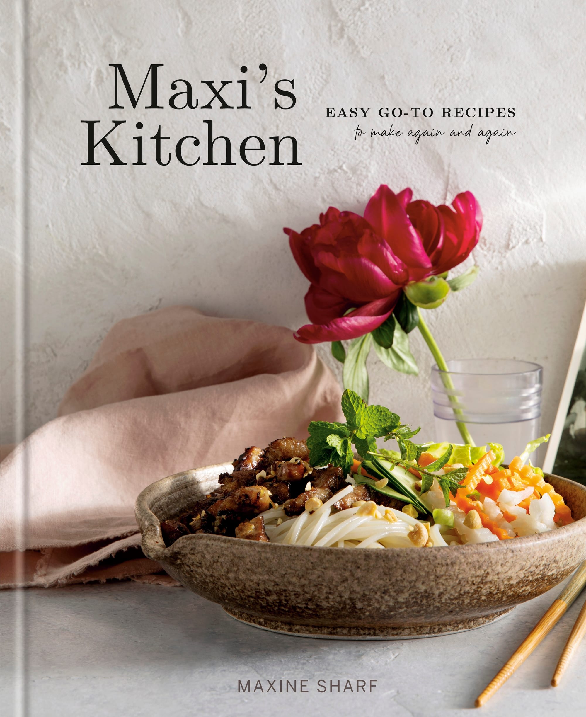 Cover of the book, Maxi's Kitchen: Easy Go-To Recipes to Make Again and Again, featuring a bowl of rice noodles with grilled meat and carrot and daikon pickles. A red flower is perched in a glass tumbler in the background.