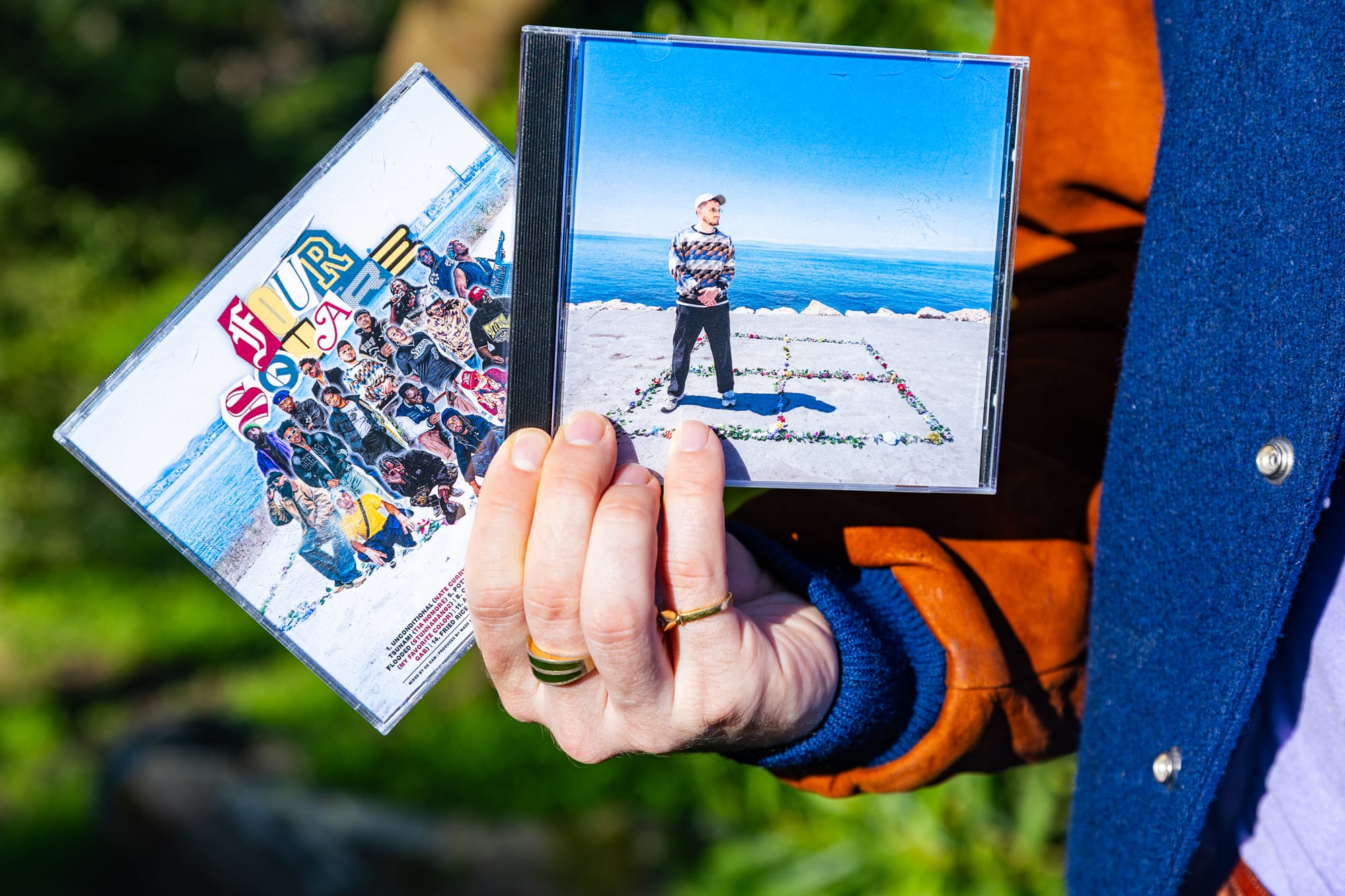 A rapper holds up two of his physical CDs for display.