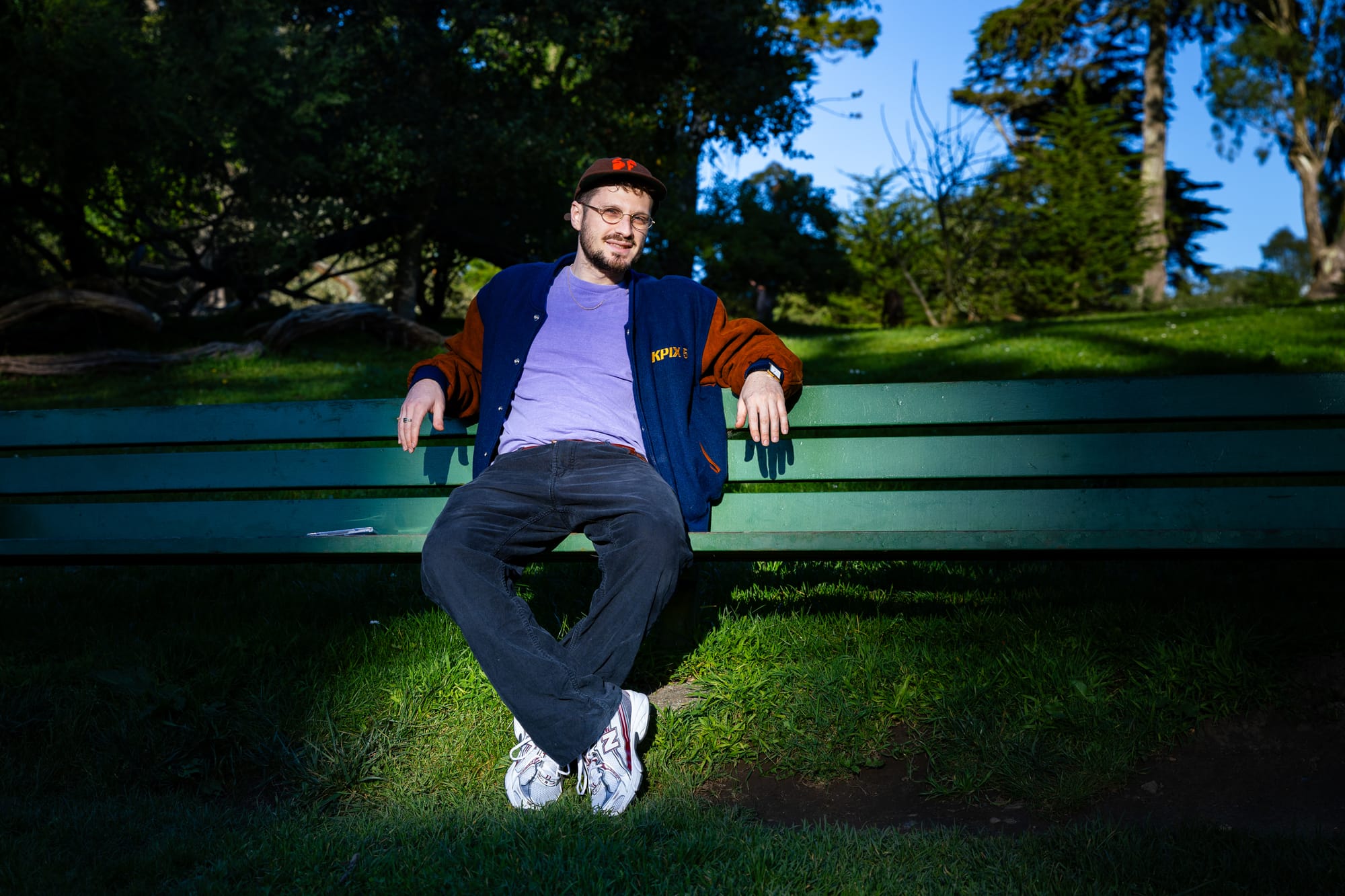 A rapper sits on a bench in a park in San Francisco.