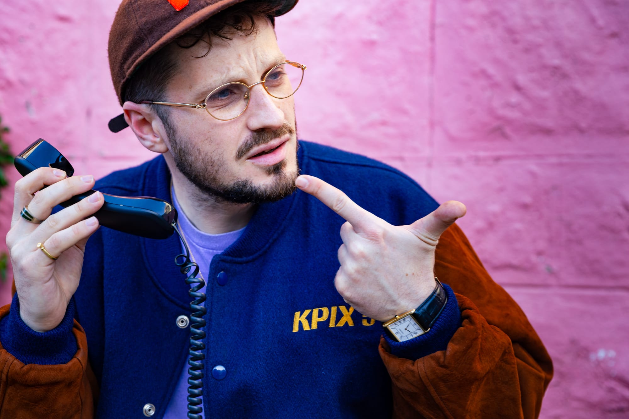A rapper playfully holds up a rotary phone and pretends to make a call.