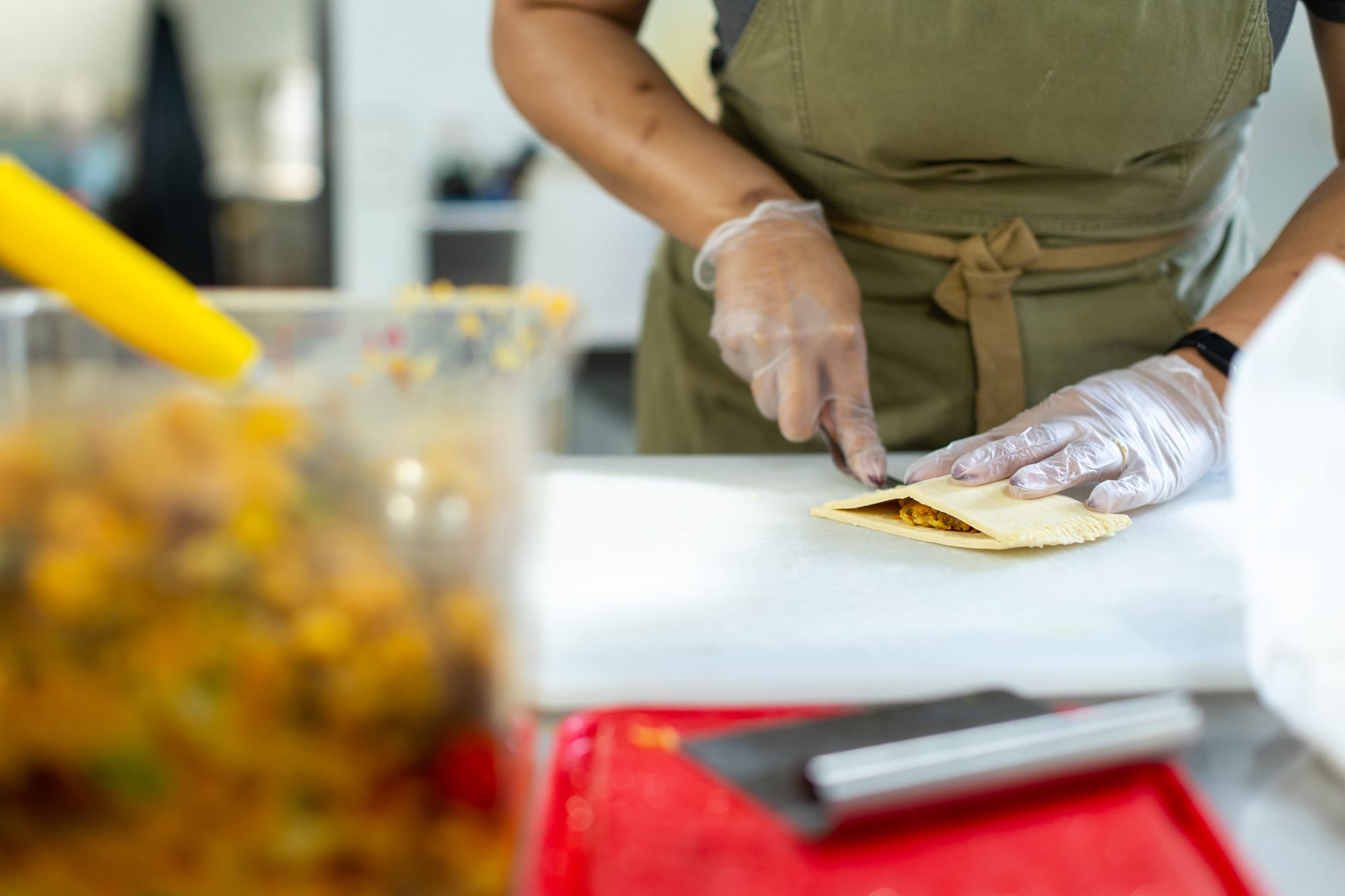 A woman in a chef's apron makes Jamaican patties.