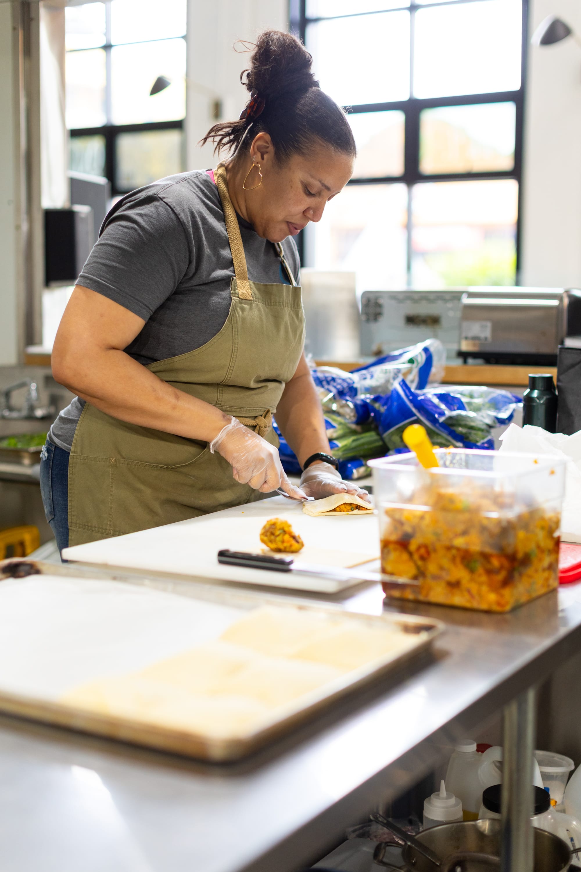 A woman in a chef's apron makes Jamaican patties.