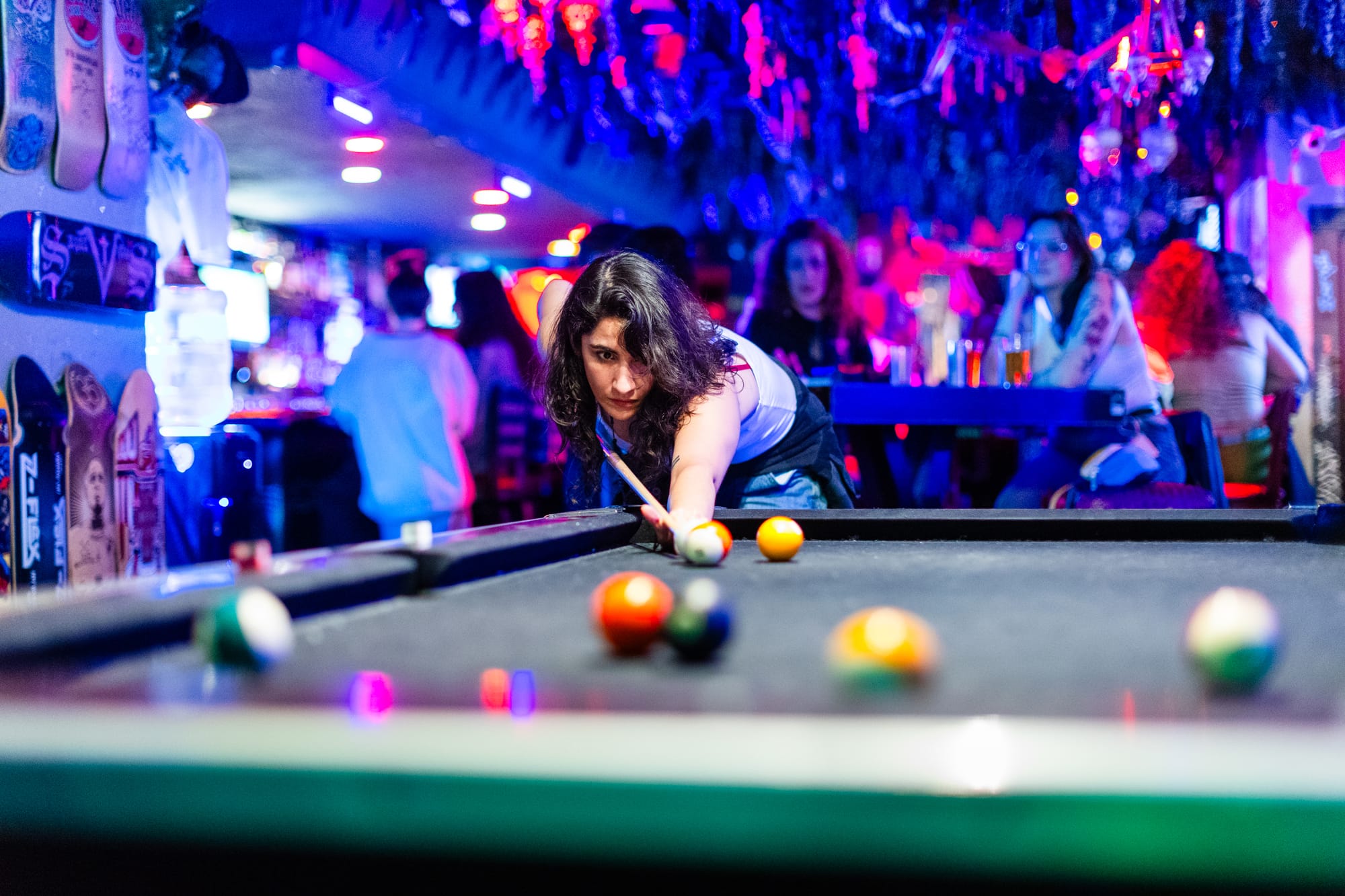 a person with dark hair is about to take a pool shot in a bar