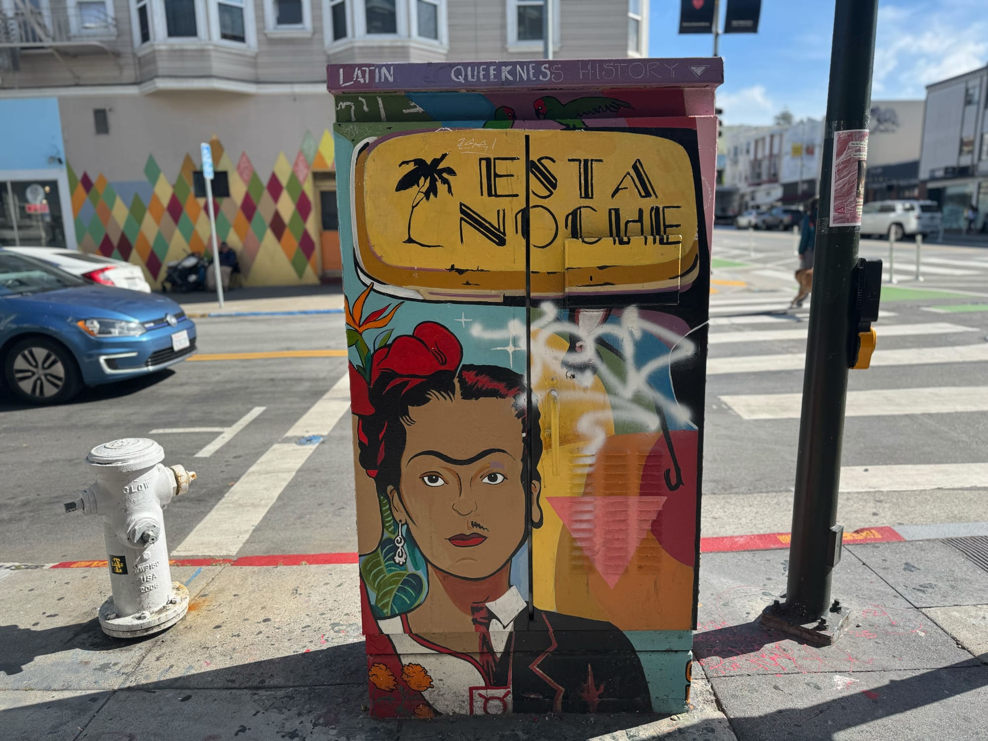 a utility box painted with the words 'esta noche' and a queer Latino performer
