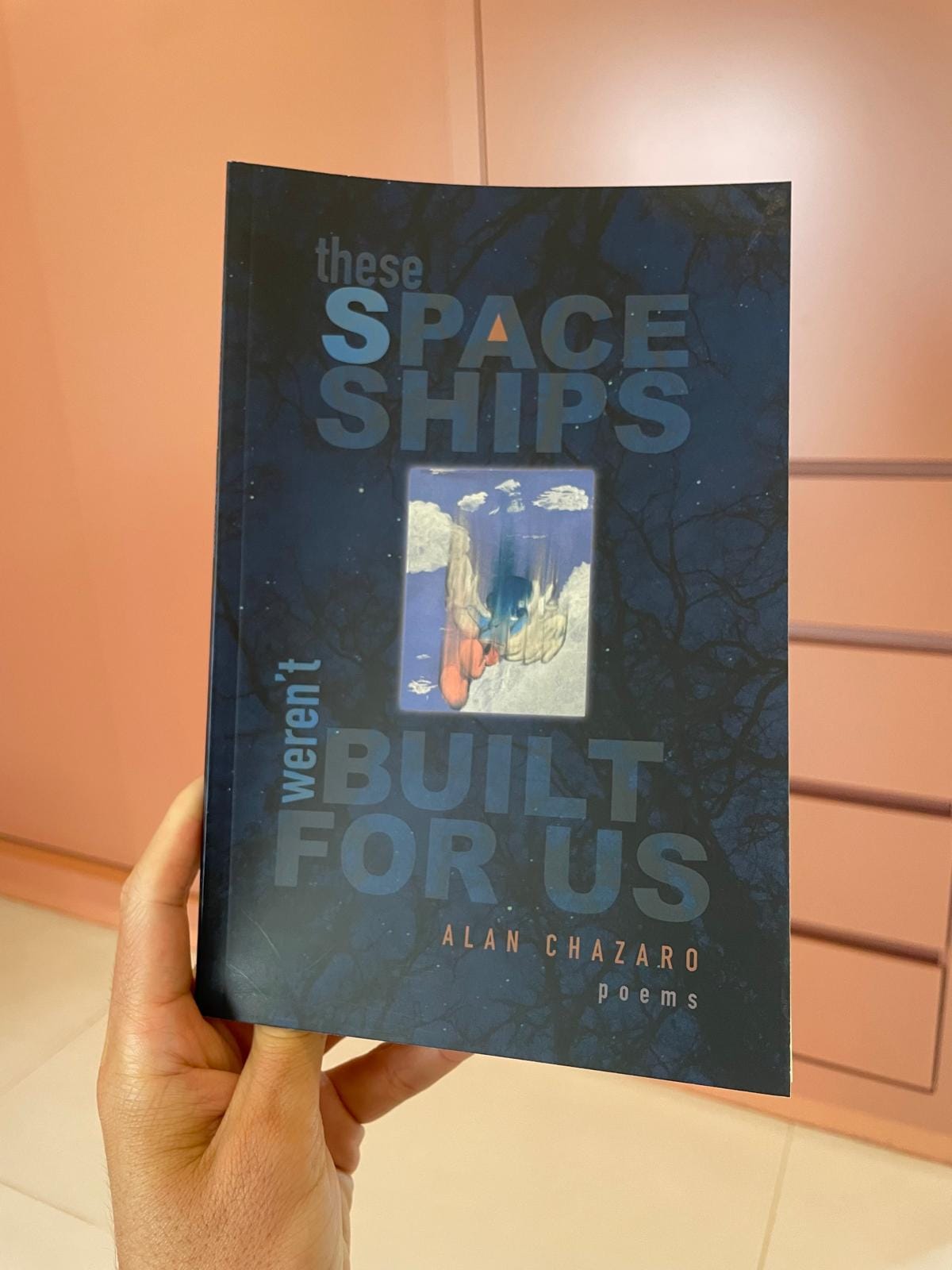 Close-up of a hand holding a book of poetry.