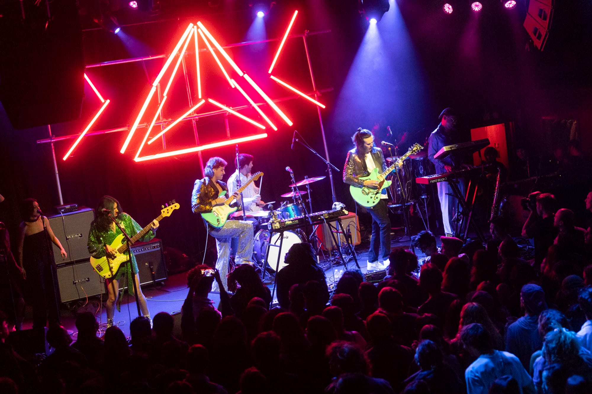 a band performs on stage with bright red neon behind them