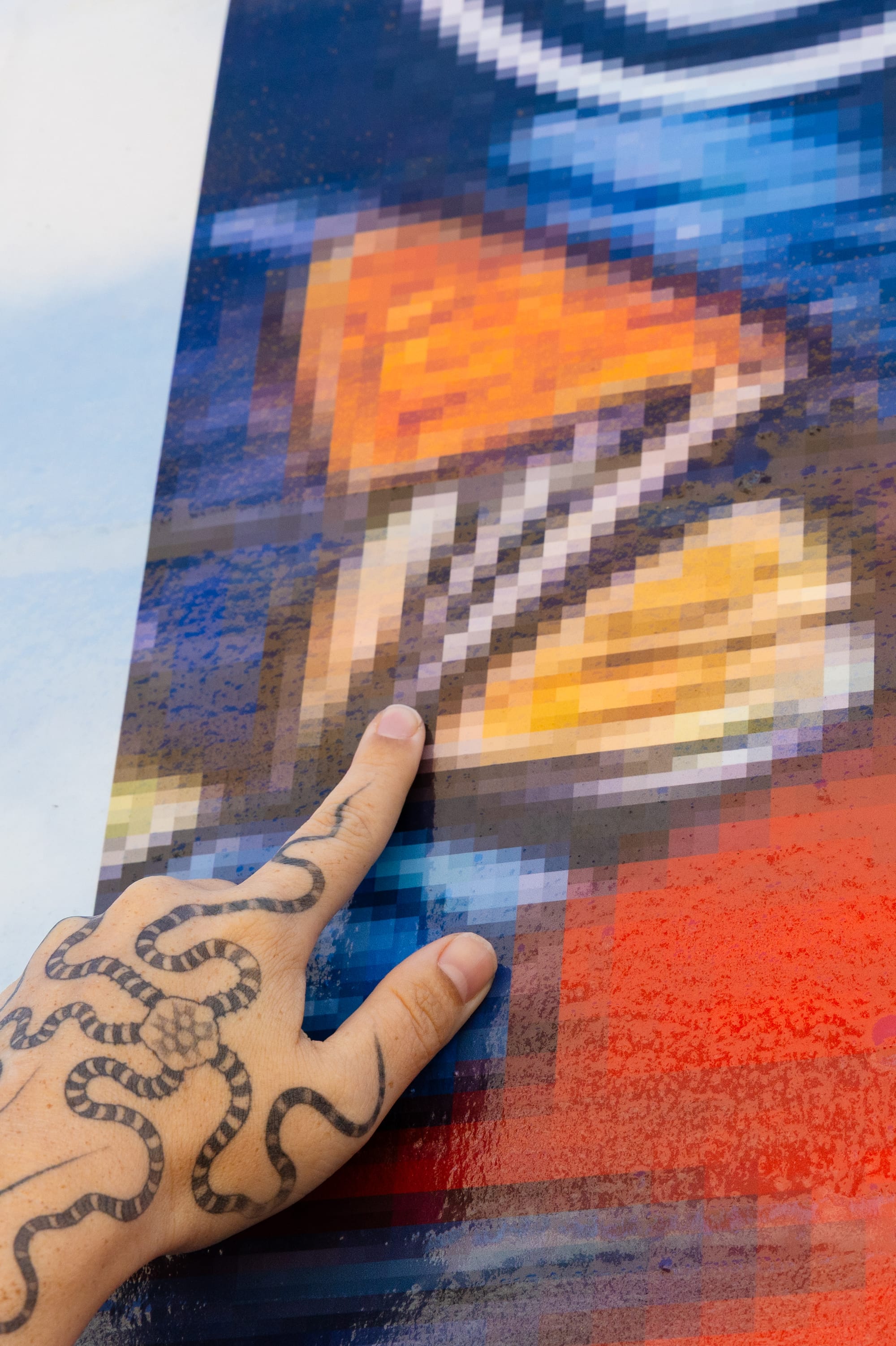A closeup of a hand pointing at a pixelated image.