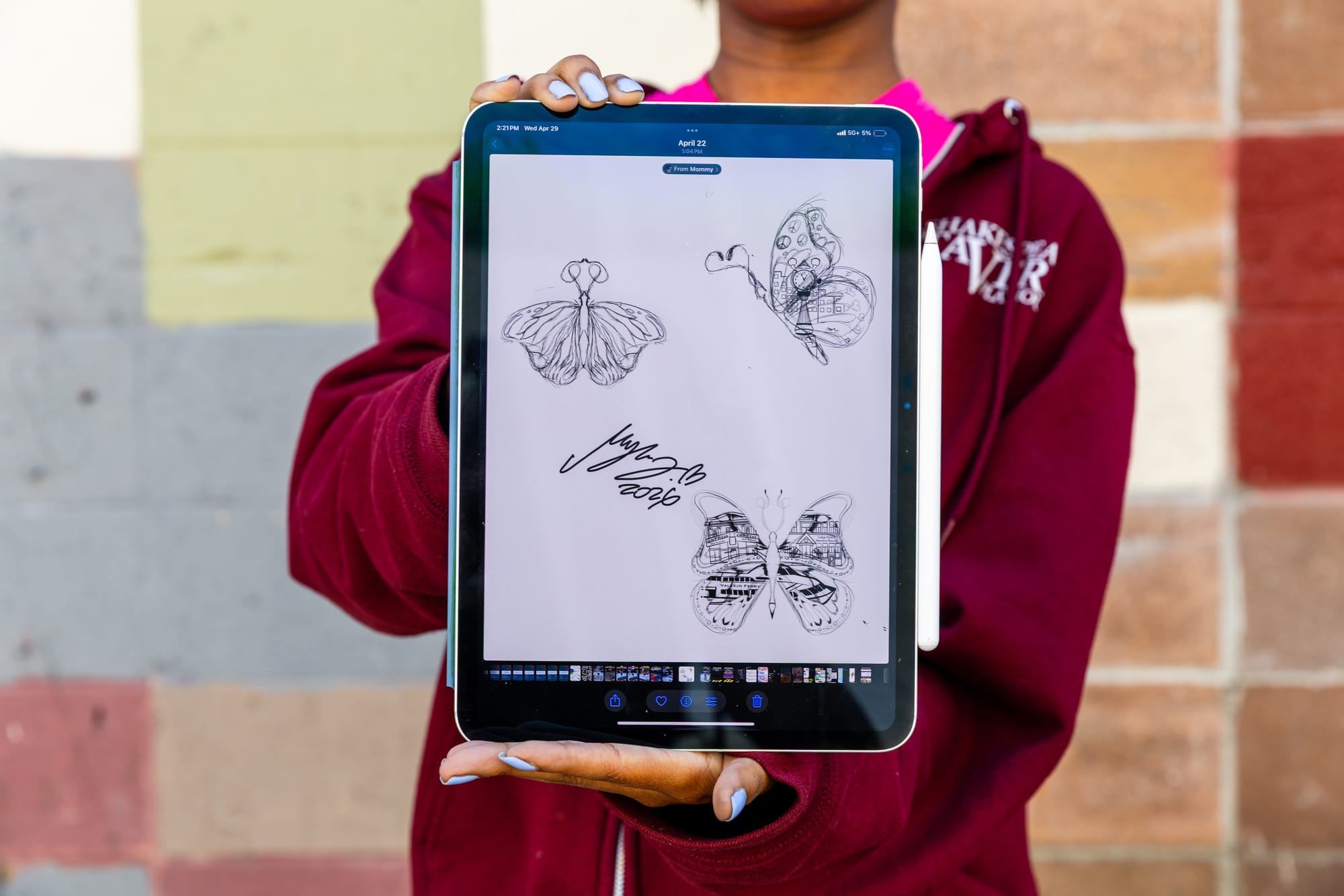 Hands holding an iPad show the sketches for the butterflies.