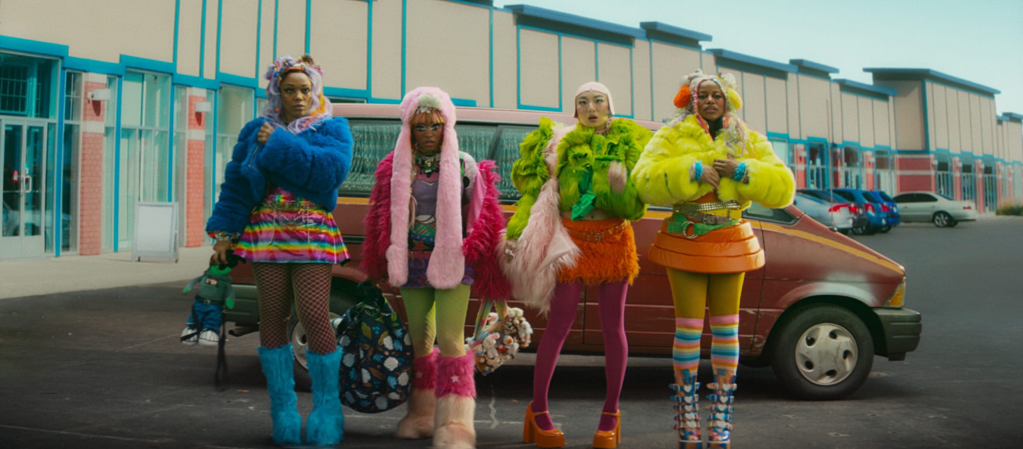 four women dressed in colorful costumes stand in front of a truck