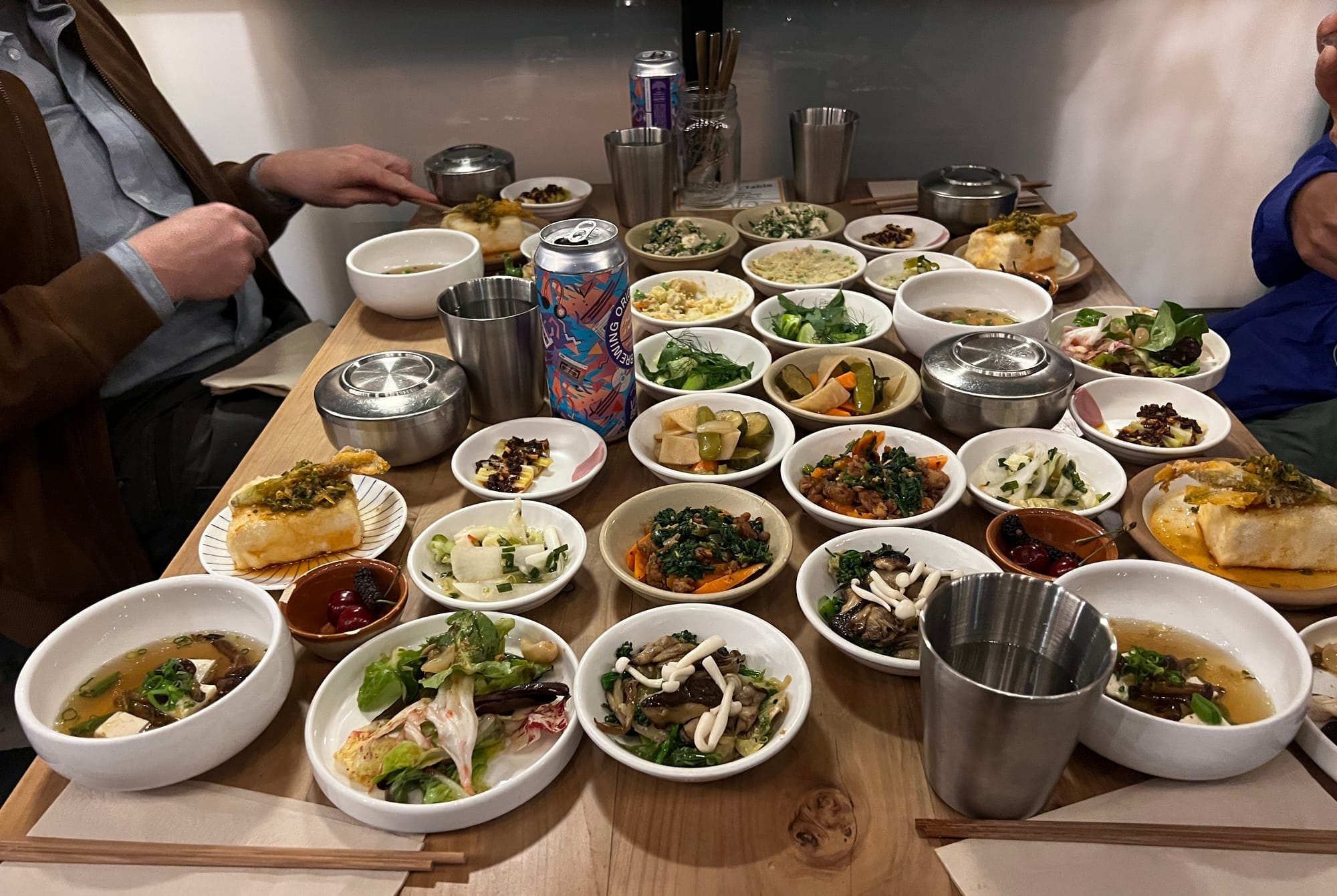 A wooden table is covered with small dishes filled with various foodstuffs.