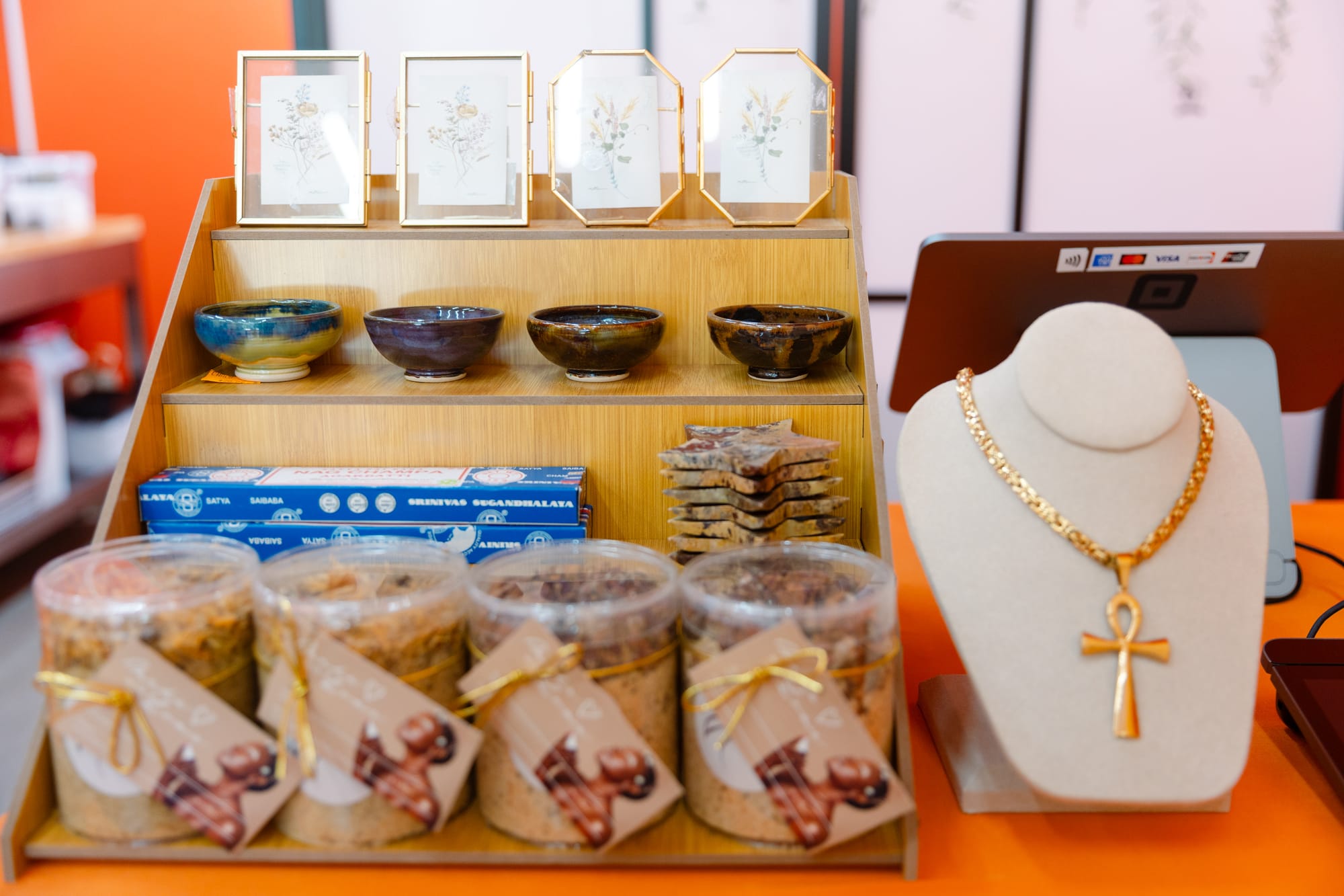 A countertop display of ceramic dishes, jewelry, cosmetics, and nag champa incense.