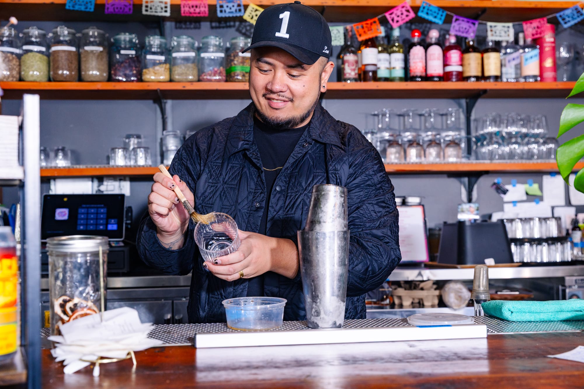 A person with a beard using a pastry brush on a bar glass.