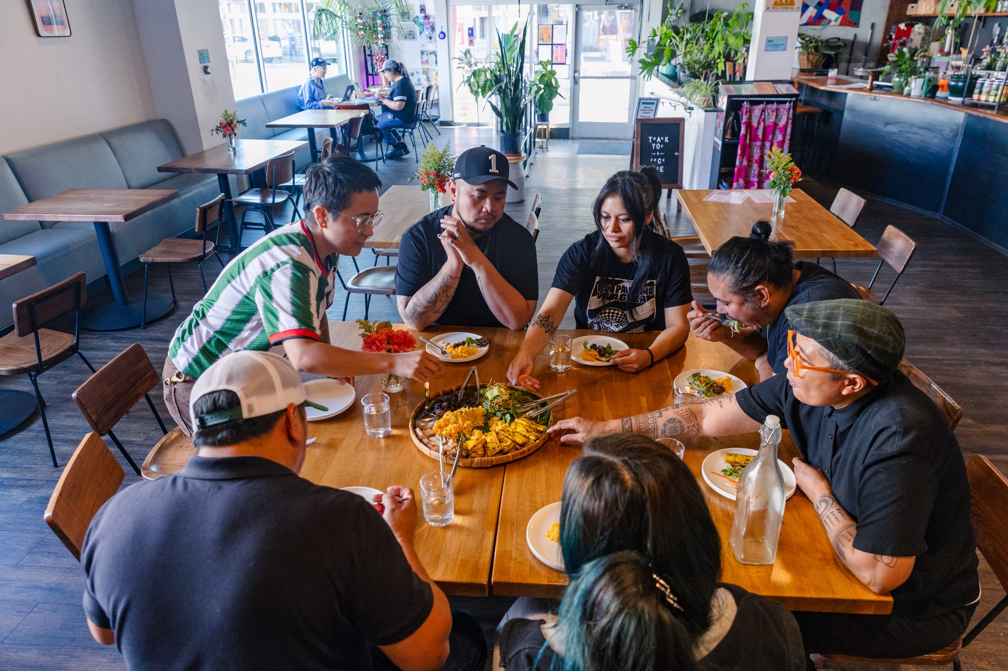 Seven people sit down to a meal inside of an otherwise empty restaurant.