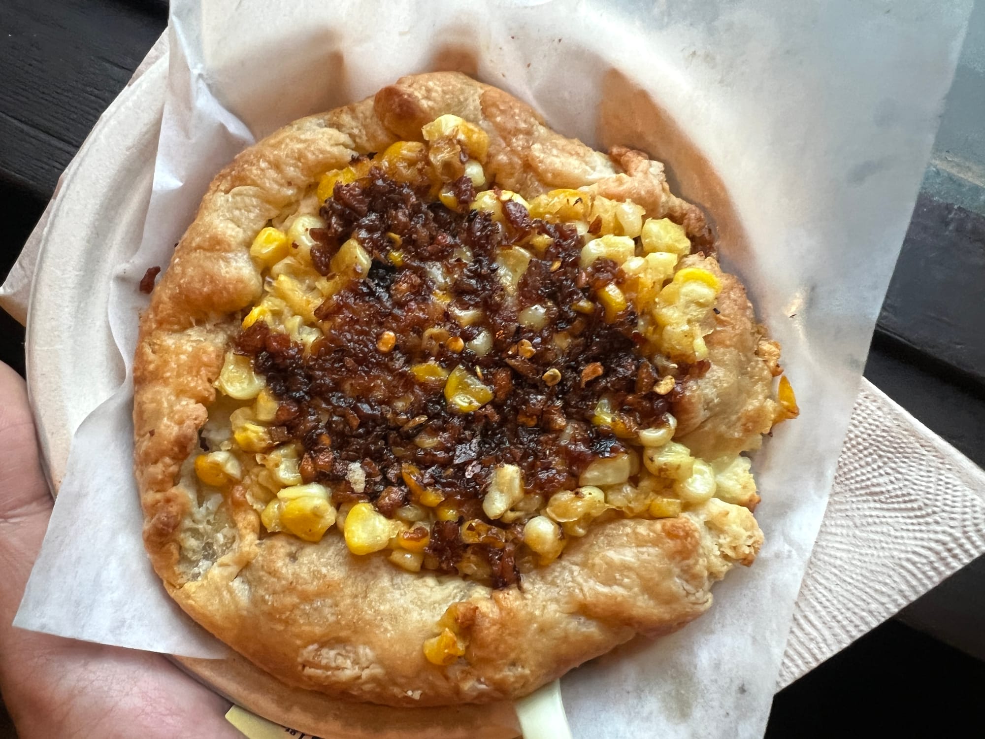 Shot of a palm-size galette topped with corn kernels and chili crisp