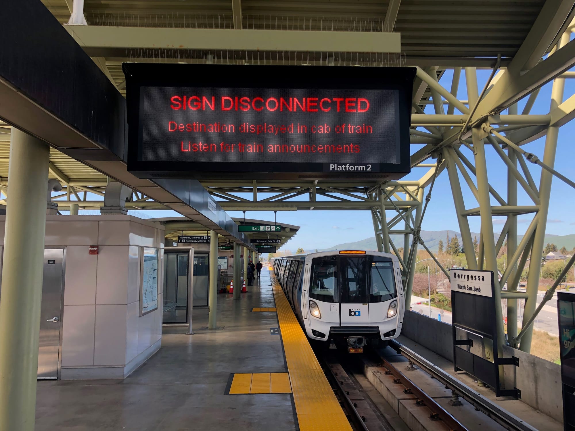 a sign at Berryessa BART Station reading 'sign disconnected' destination displayed in cab of train listen for announcements with a bart train pulled into the station