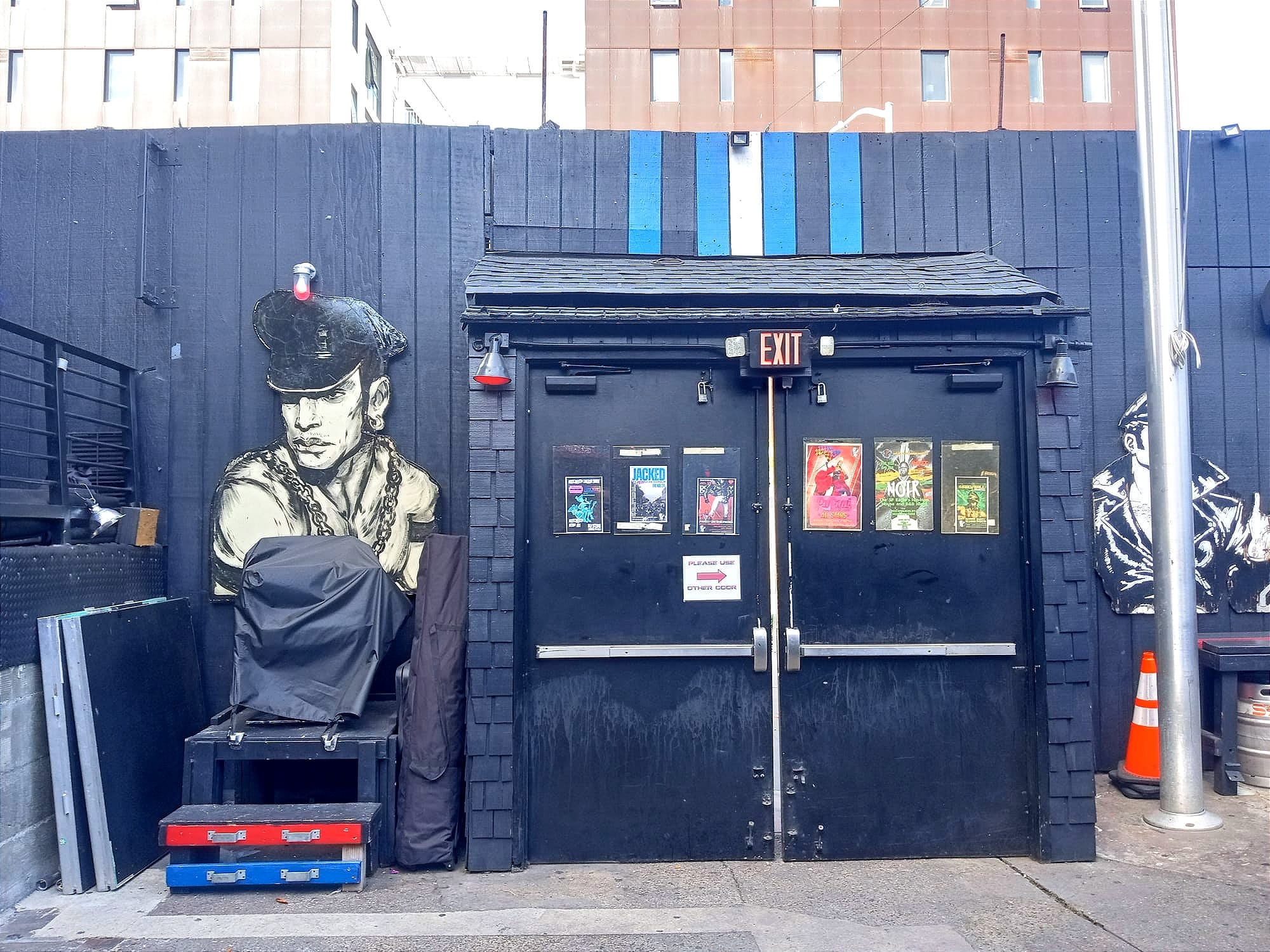the black exterior of a building with double doors and a illustrations of men in leather and chains
