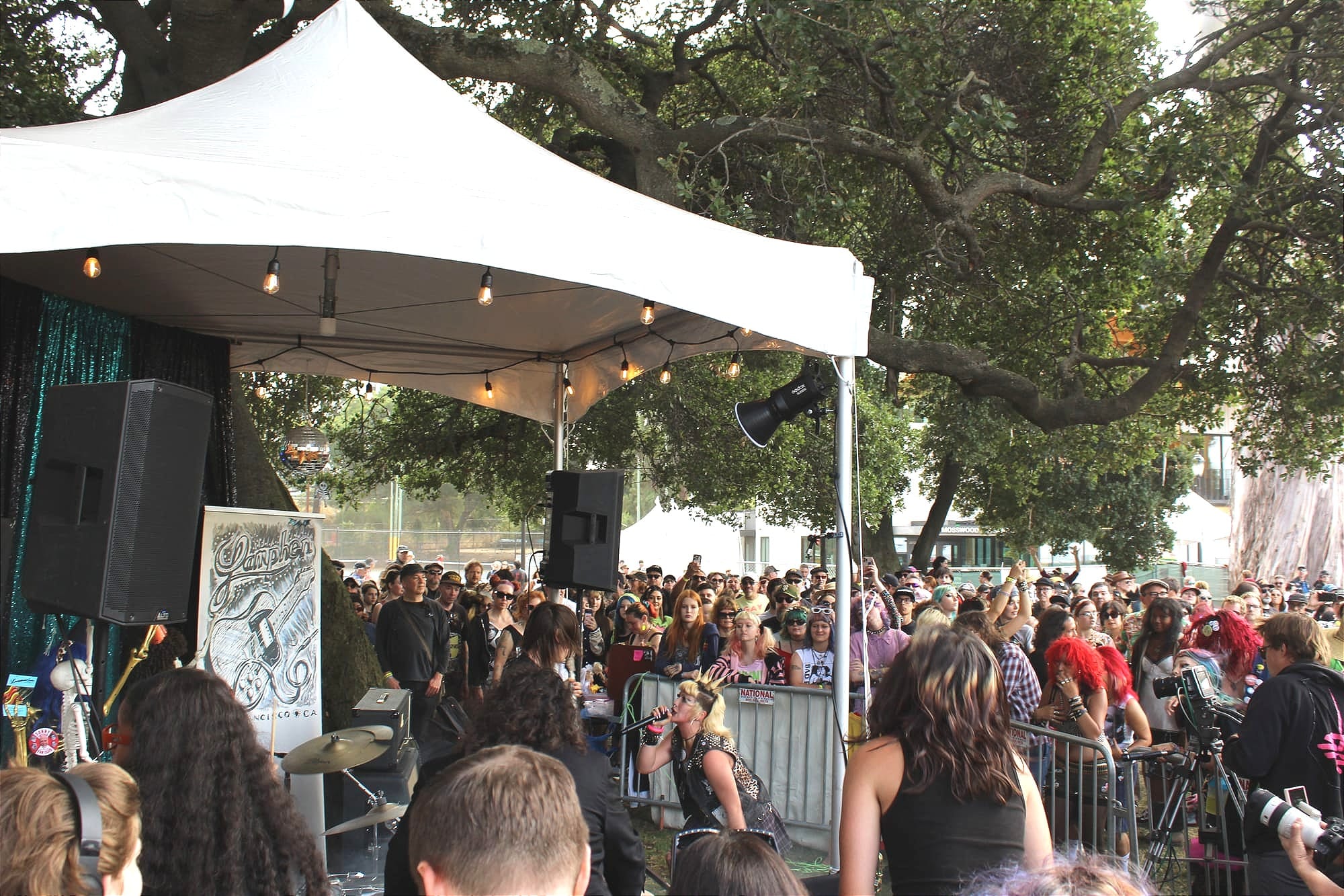 a young woman sings under a small festival tent surrounded by people