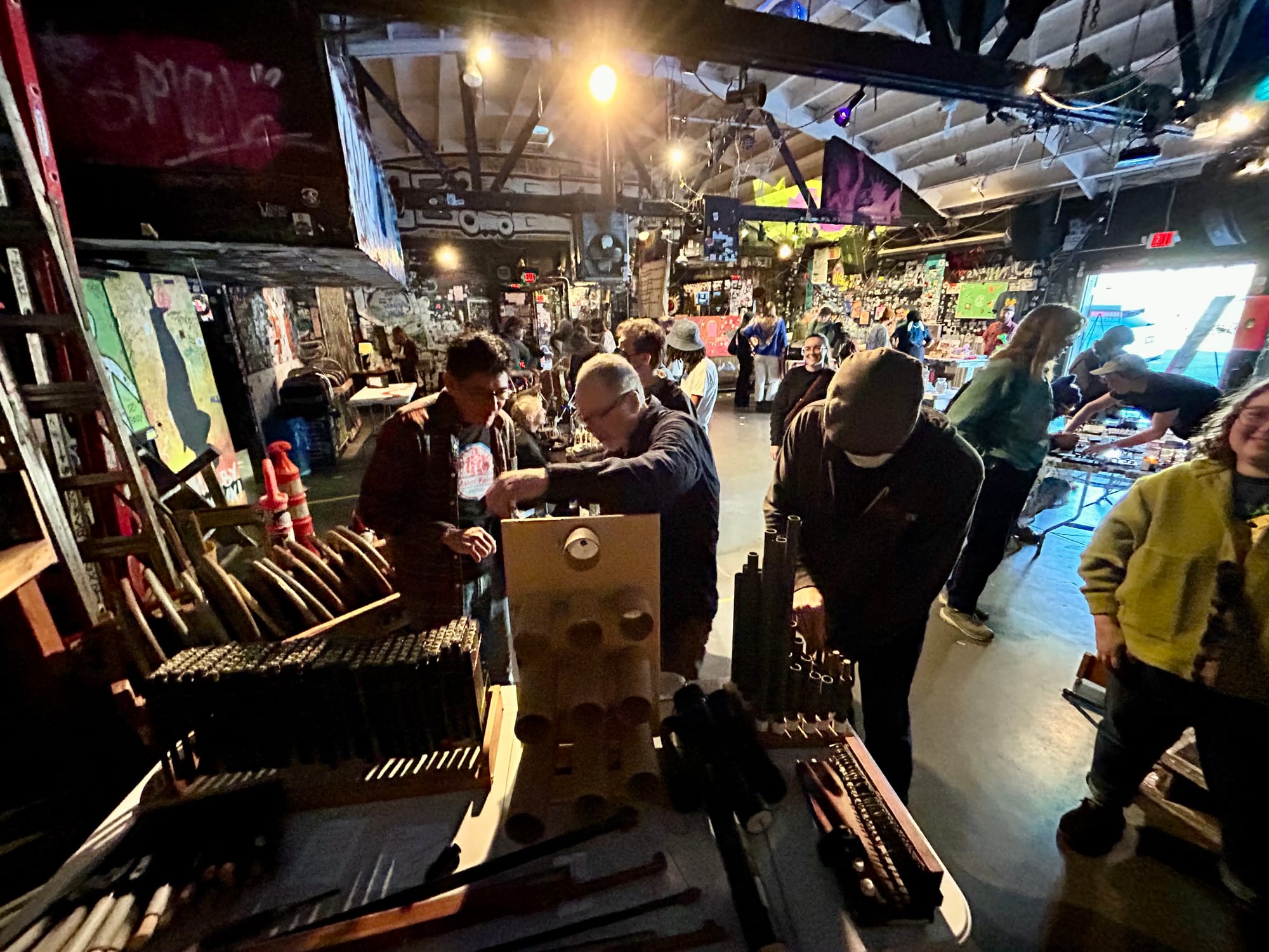 people touch weird instruments in an audio carnival at a punk club
