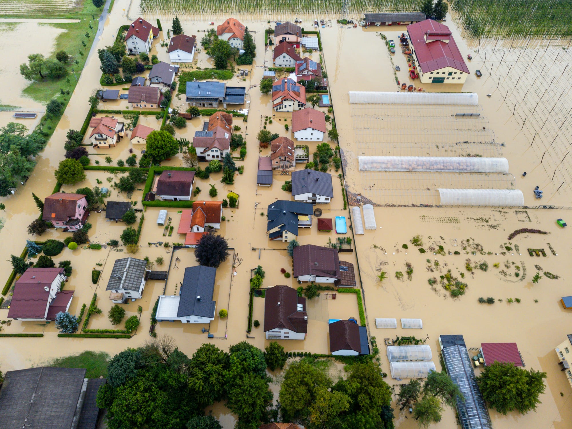 A suburban neighborhood submerged in muddy floodwaters.
