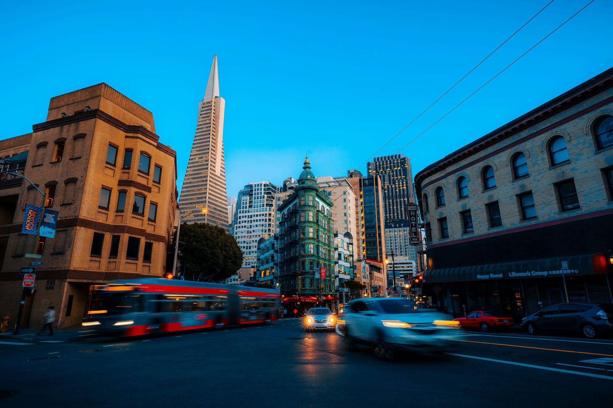 a car and a bus go different directions on an evening in downtown San Francisco