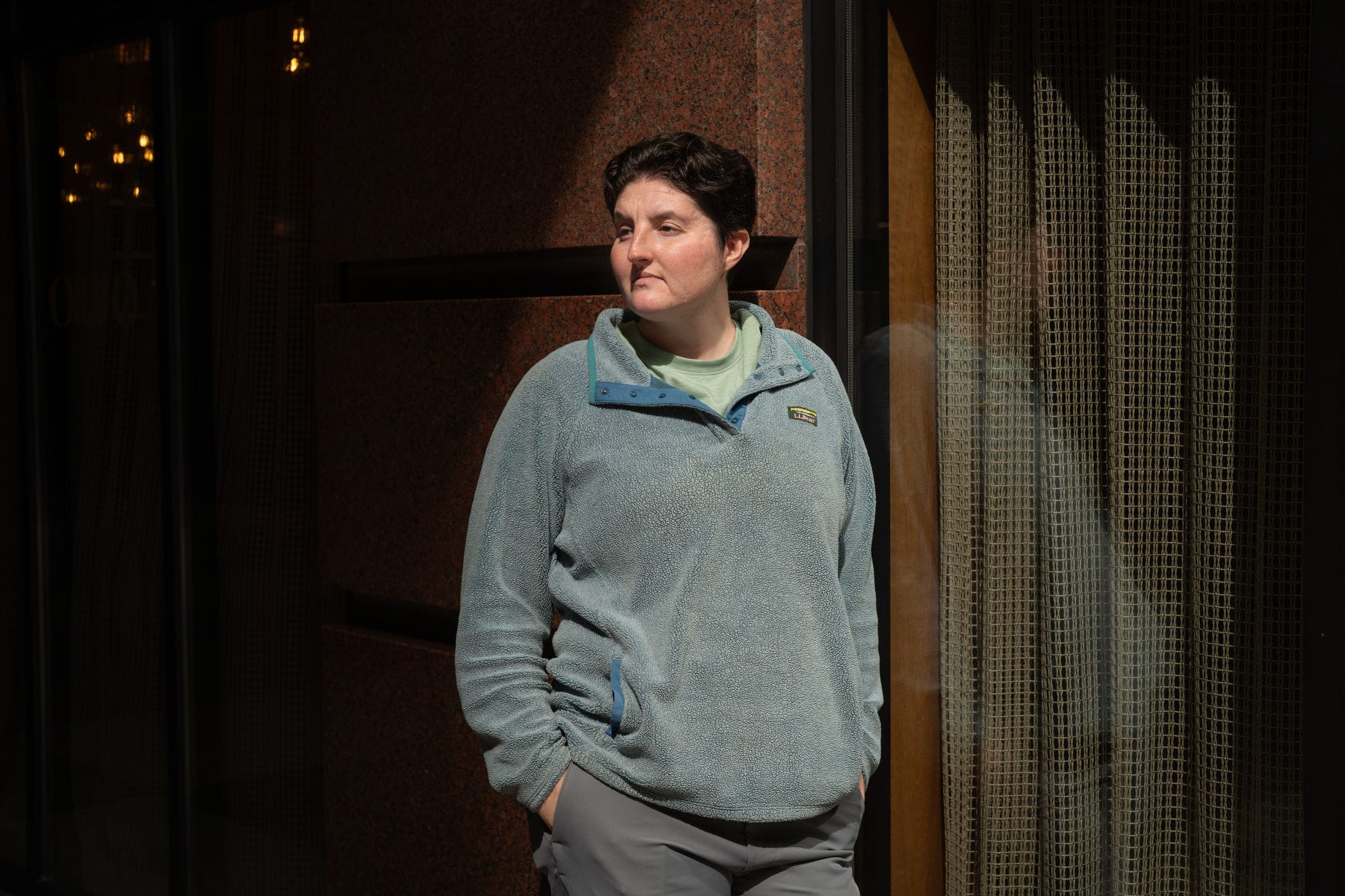 Woman with short hair standing in front of a building.