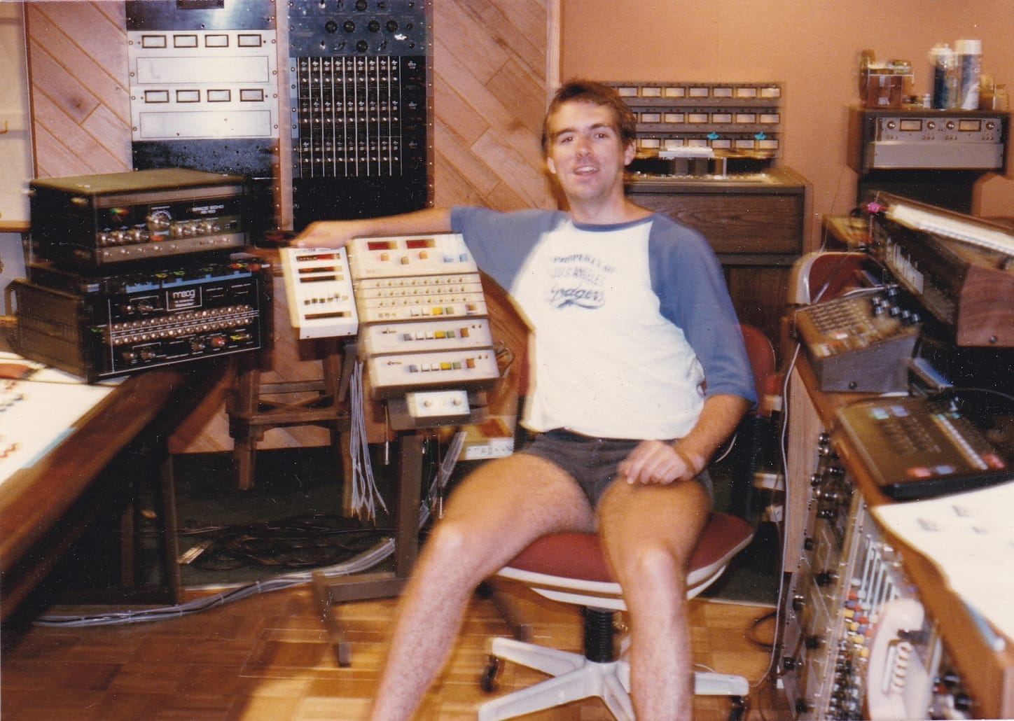 a man in shorts sits in a recording studio in a photograph from 1985