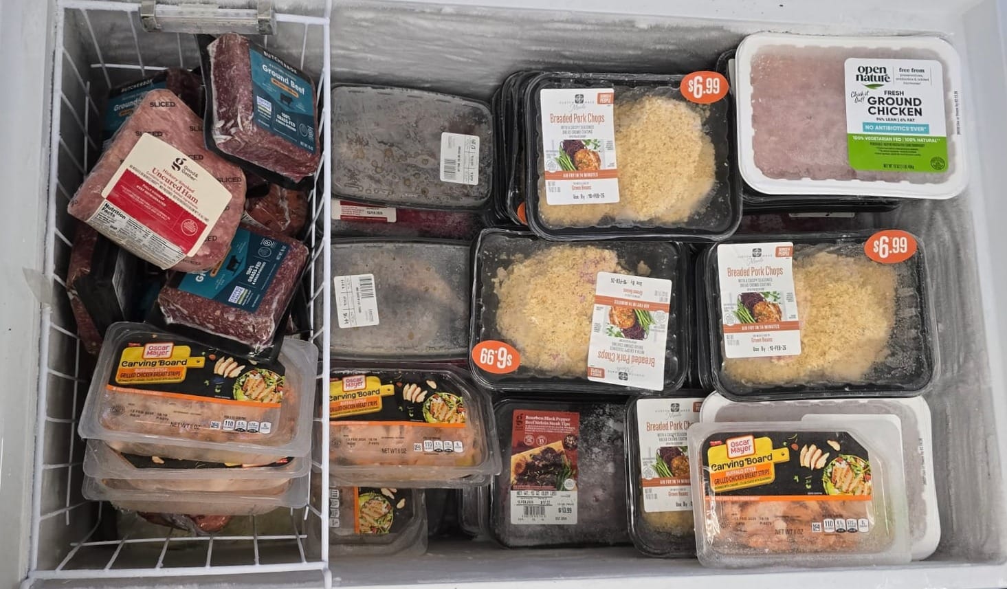 ground chicken, breaded pork chops, and other types of meat sit in a freezer