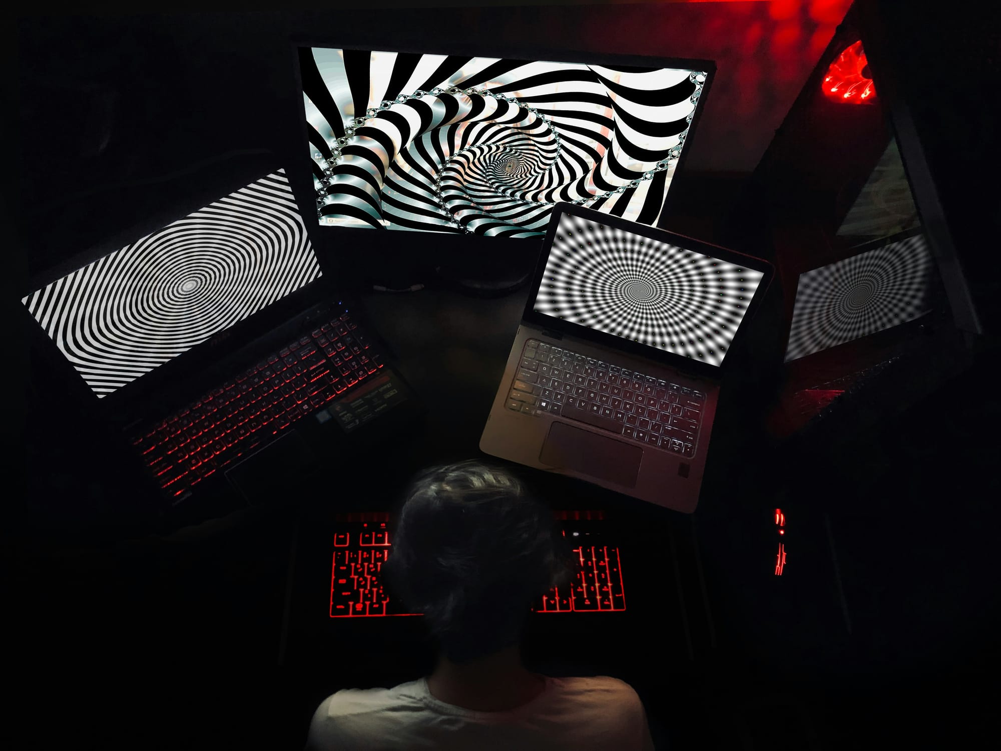 a person sitting in front of four computers with crazy black and white symbols on them