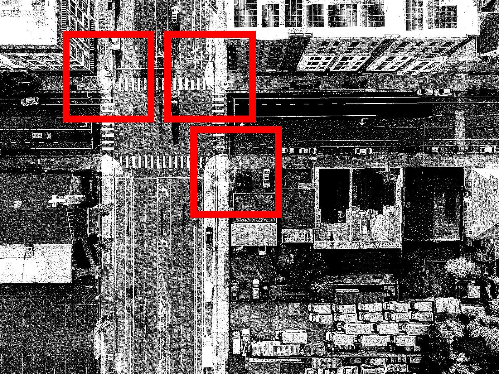 a black and white aerial drone image of a city intersection with red square outlines