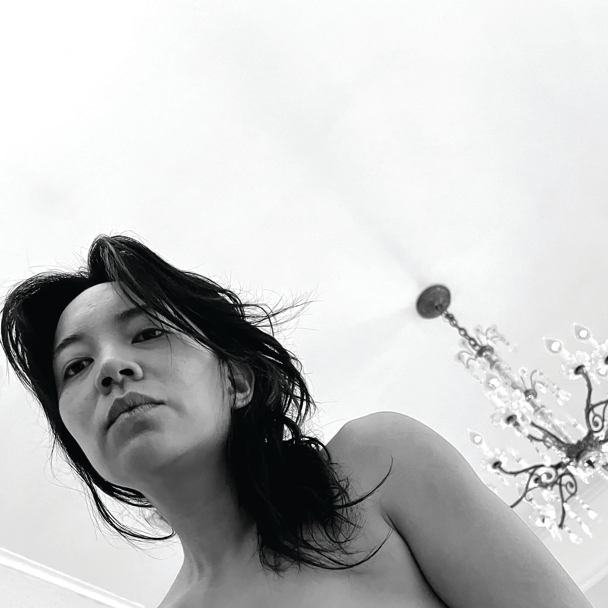 Woman looking down from above, with a chandelier in the background.